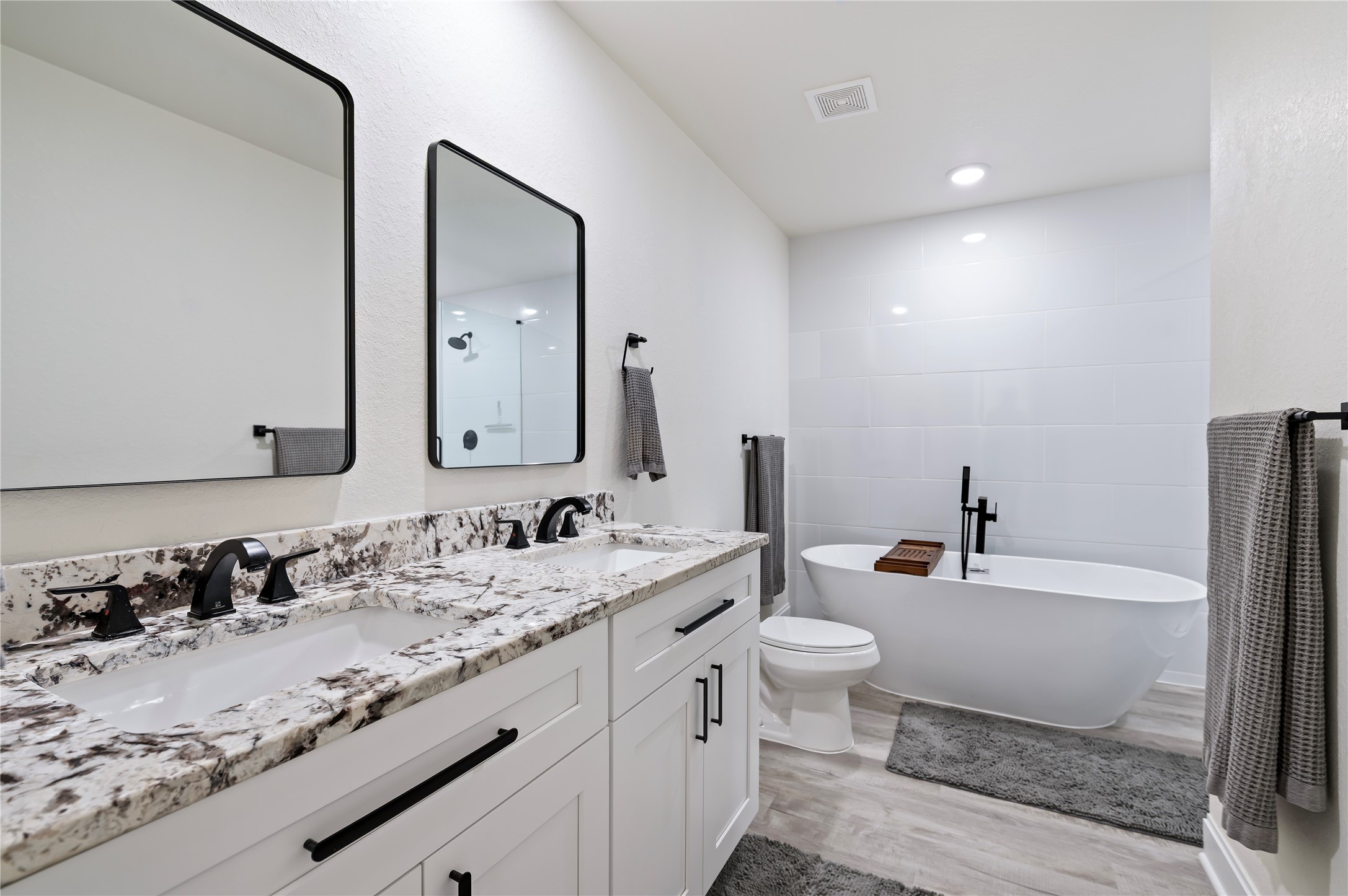 Upstairs full bathroom features large soaking tub with separate shower, Alaskan White Granite countertops with custom hardware, ample storage drawers and dual vanities with framed mirrors.