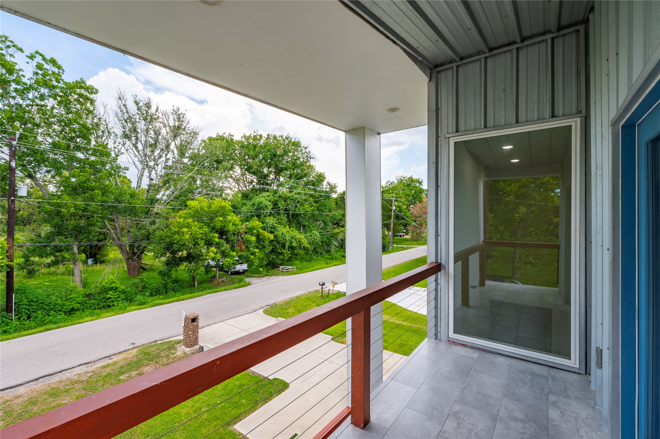 Private 2nd story covered patio features 3/4" conduit horizontal railing on balcony overlooking the front of the property with tile flooring.