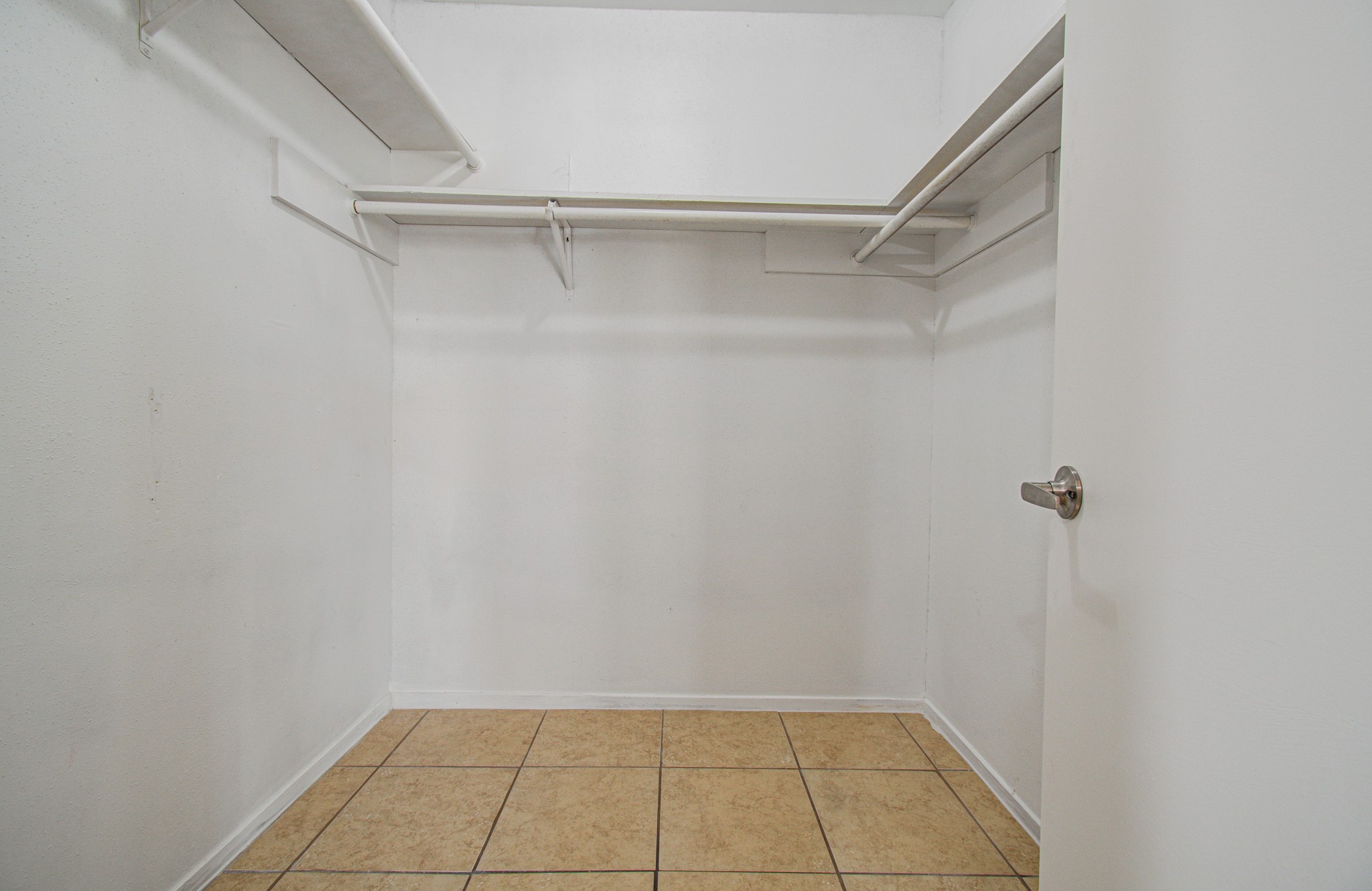 Spacious walk-in closet featuring ample shelving and tiled flooring for organized storage.