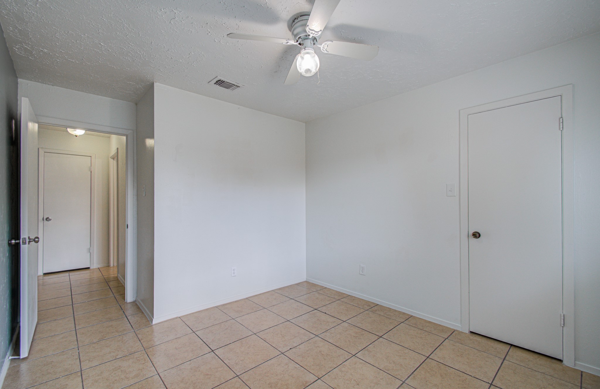 Bright and airy room featuring neutral tile flooring, a ceiling fan for comfort, and ample natural light, offering a versatile space for any purpose.