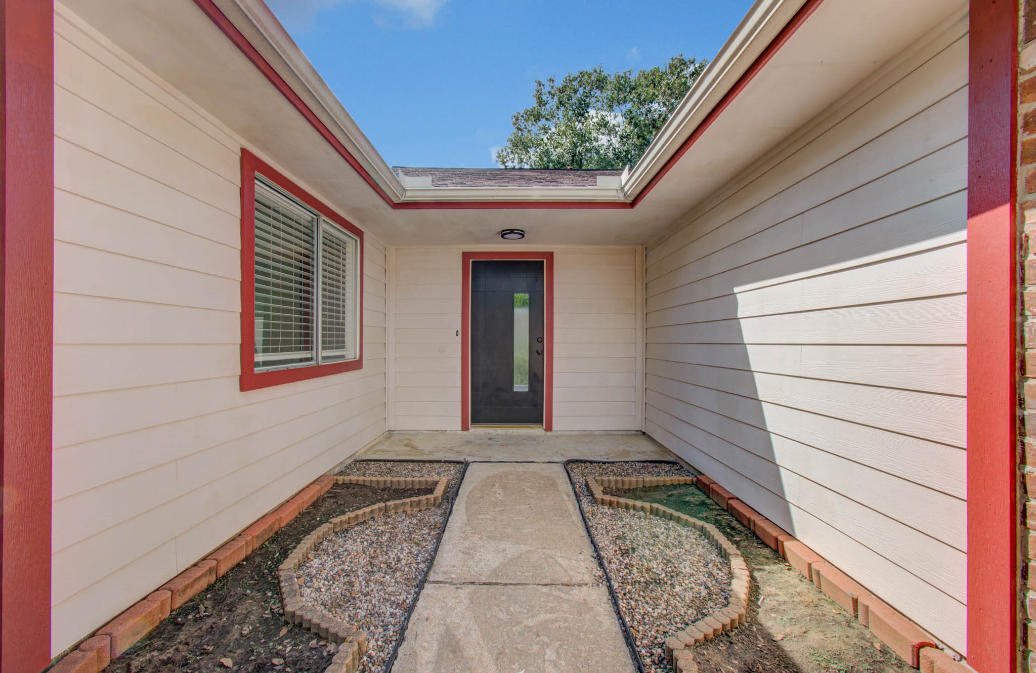 Charming entrance with a welcoming pathway, framed by fresh landscaping and accented with bold red trim, leading to a modern glass door. Charming entrance with a welcoming pathway, framed by fresh landscaping and accented with bold red trim, leading to a modern glass door.