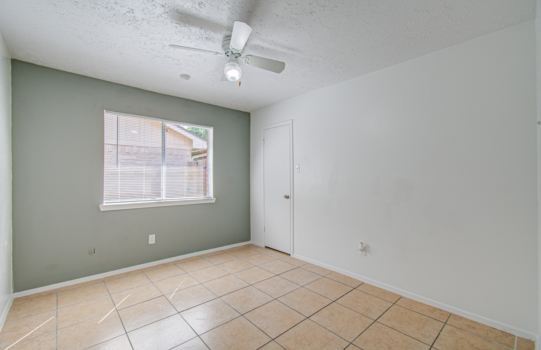 Bright room with tile flooring, a ceiling fan, and a large window allowing natural light.