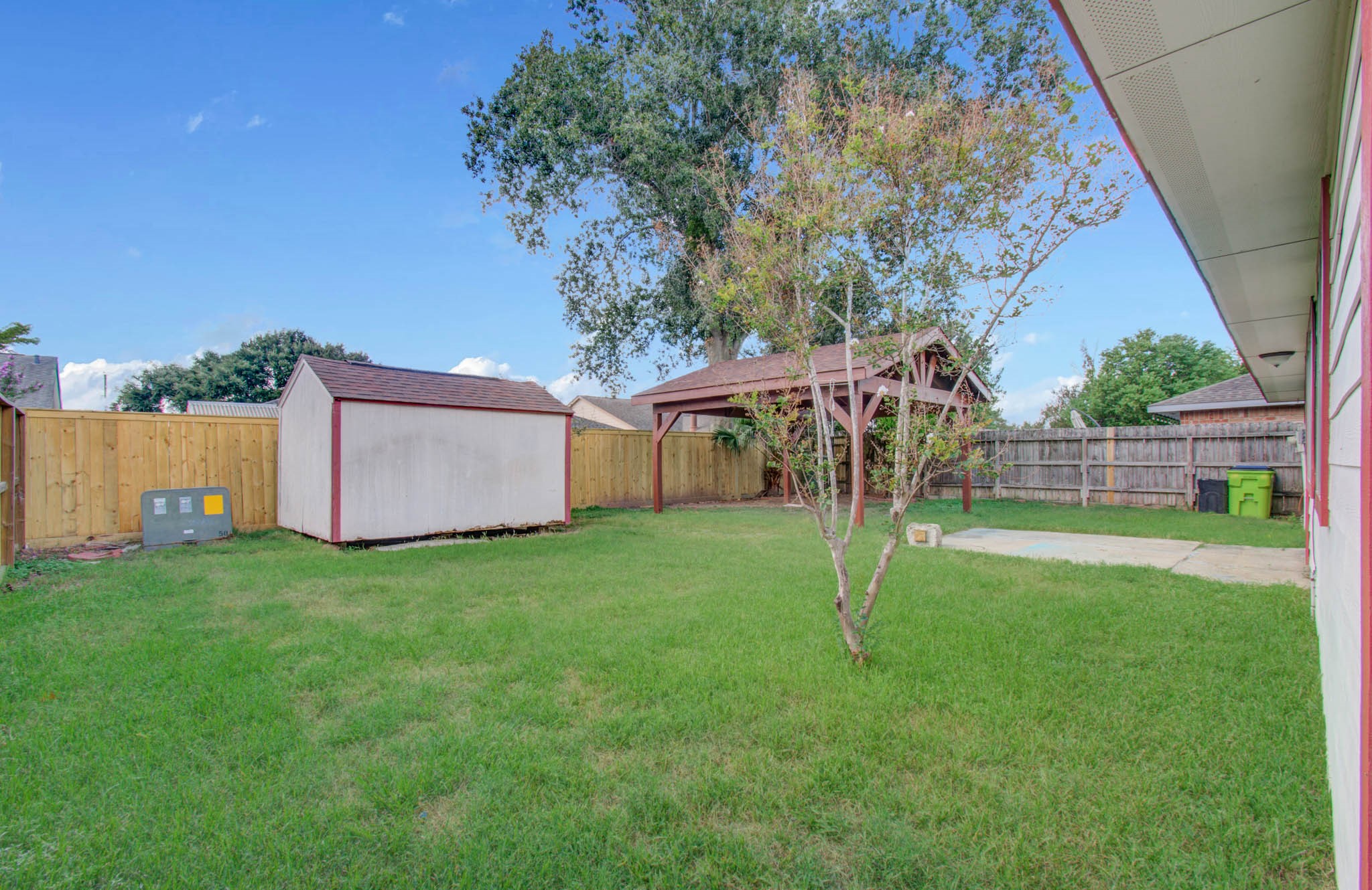 Spacious backyard with lush grass, a convenient storage shed, and a charming gazebo, perfect for outdoor gatherings and relaxation.