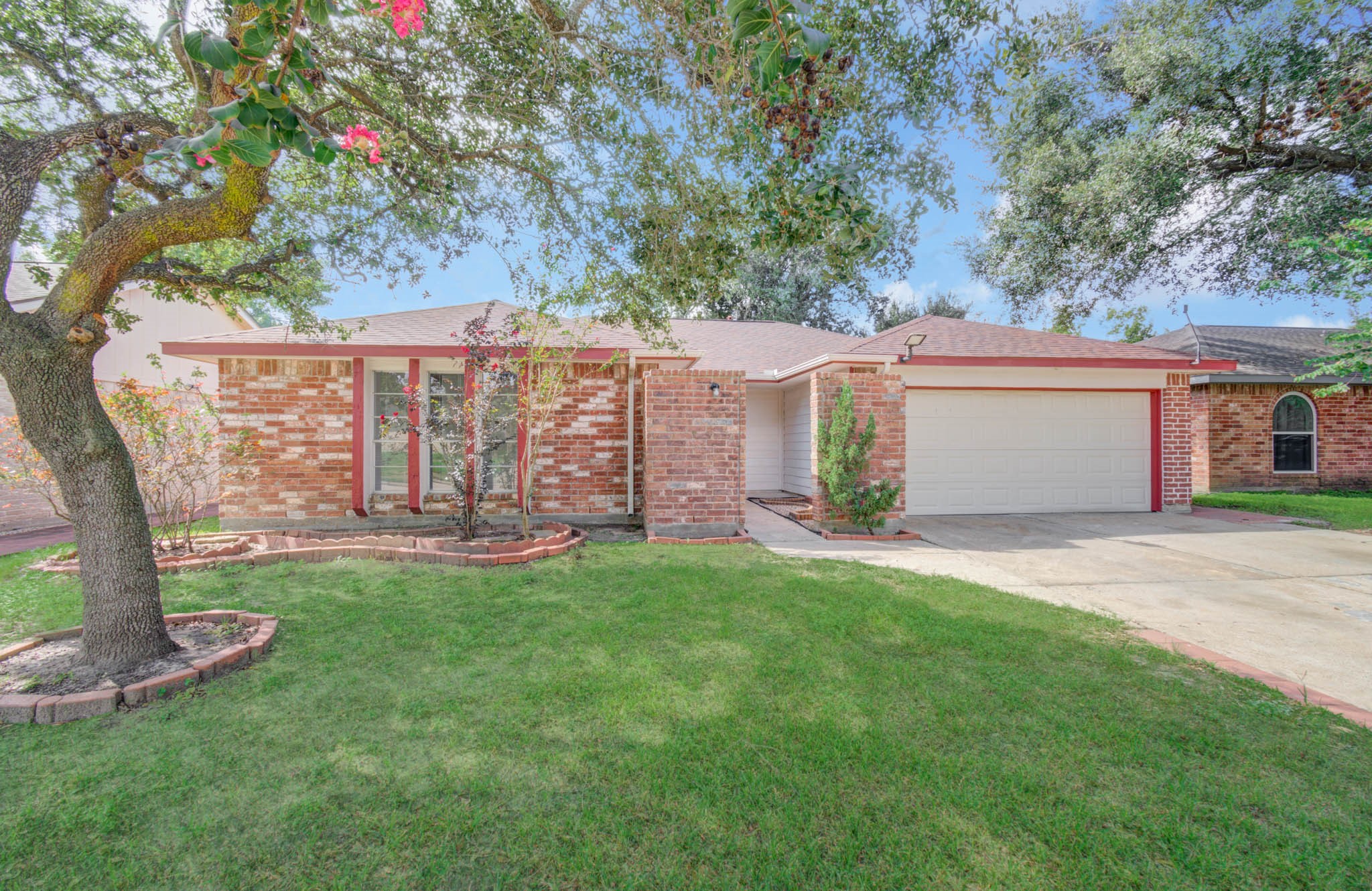 Charming single-story brick home with a two-car garage, lush front yard, and mature trees providing shade and curb appeal. Charming single-story brick home with a two-car garage, lush front yard, and mature trees providing shade and curb appeal.