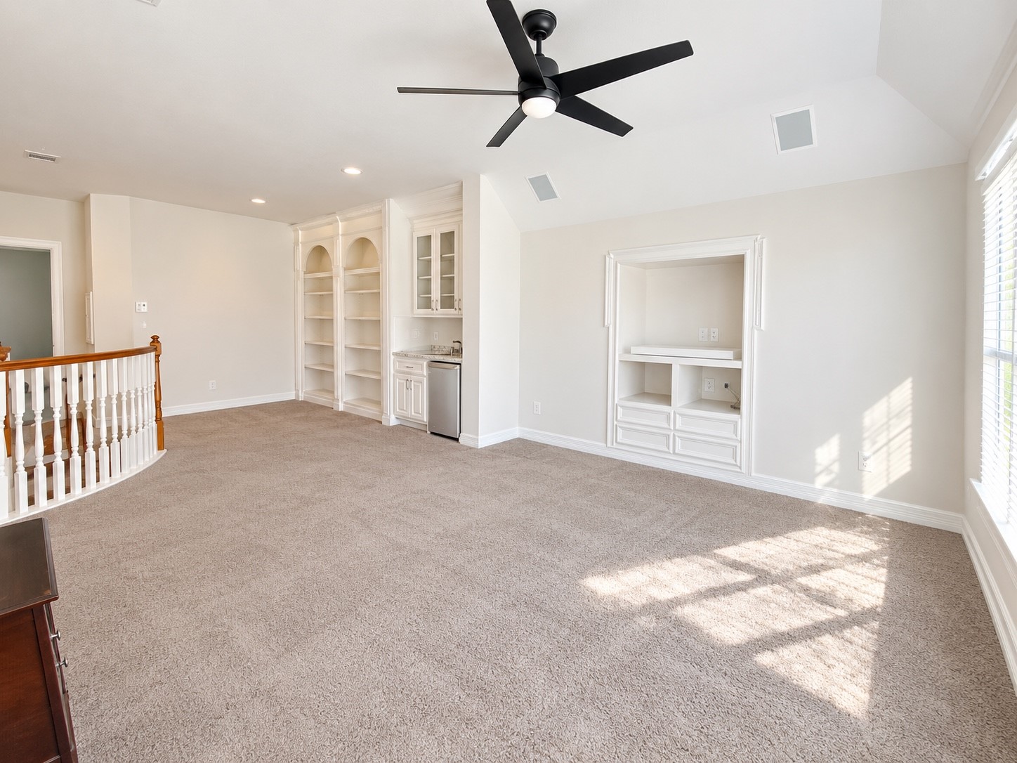 Spacious game room featuring built-in shelving, a wet bar, and ample natural lightperfect for entertaining.