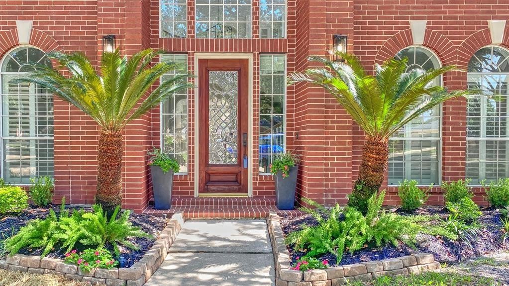 Elegant front door framed by lush greenery, offering a warm and inviting entrance.
