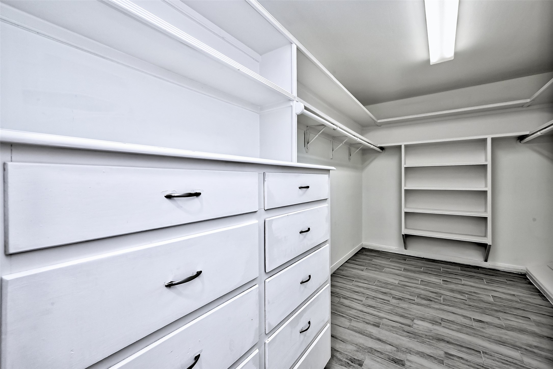 Primary walk in closet with build in dresser and shelf