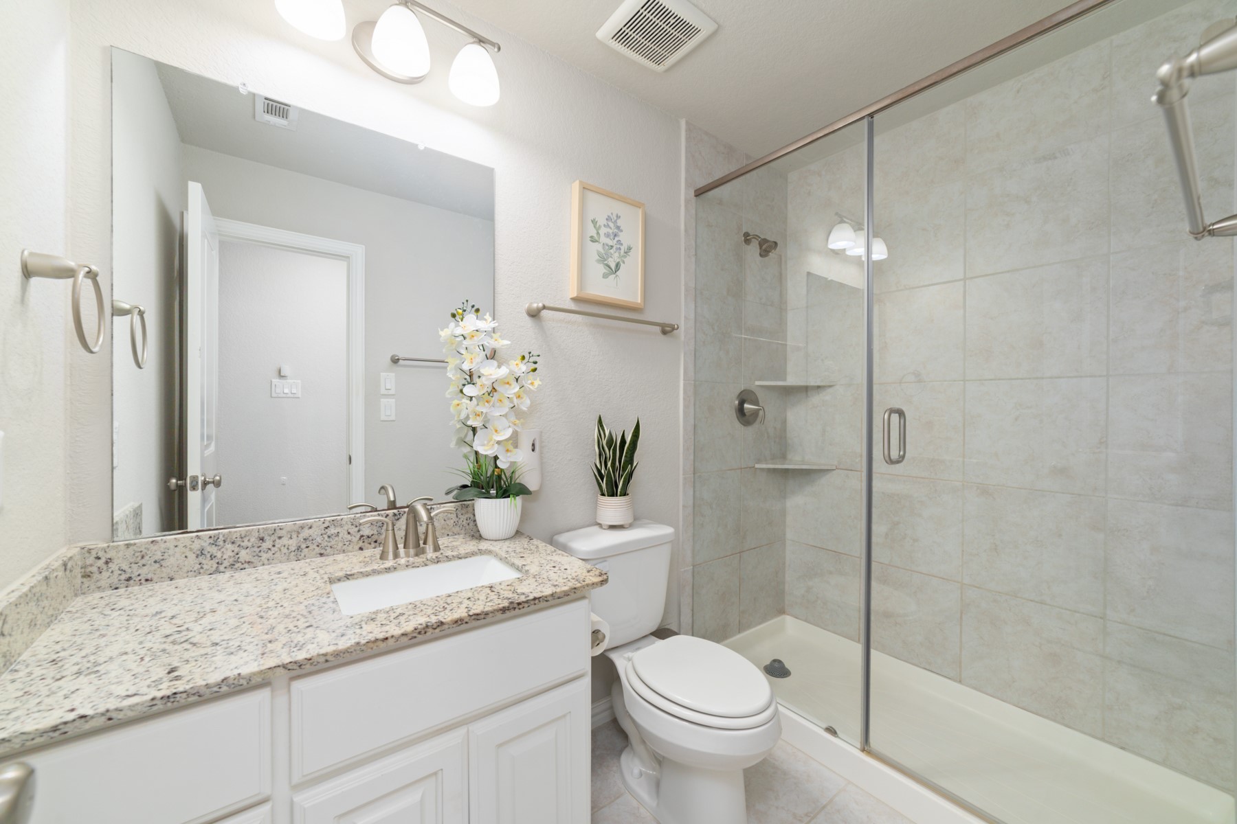 Modern bathroom featuring a spacious glass-enclosed shower, and elegant granite countertop.