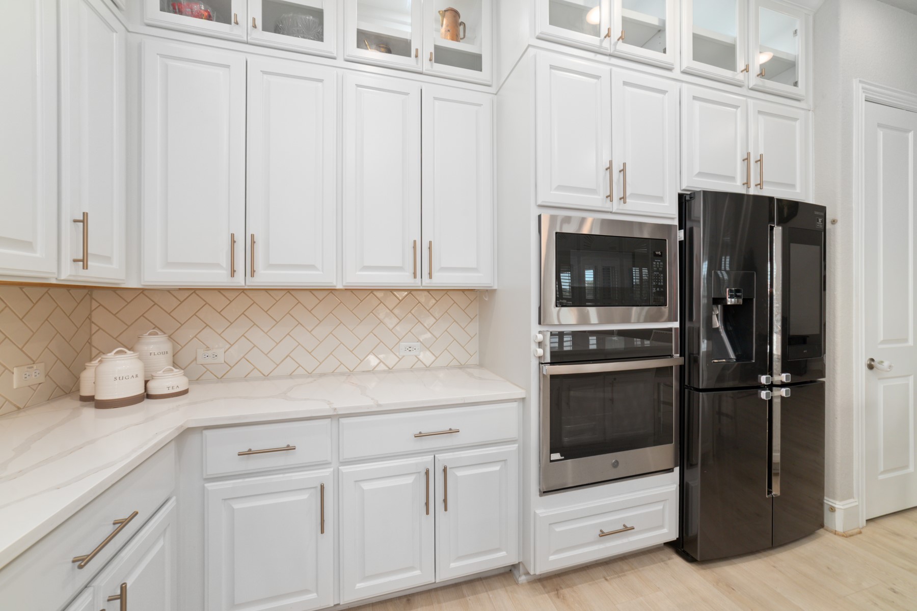 Elegant kitchen featuring sleek black appliances, and a chic herringbone backsplash for a modern touch.