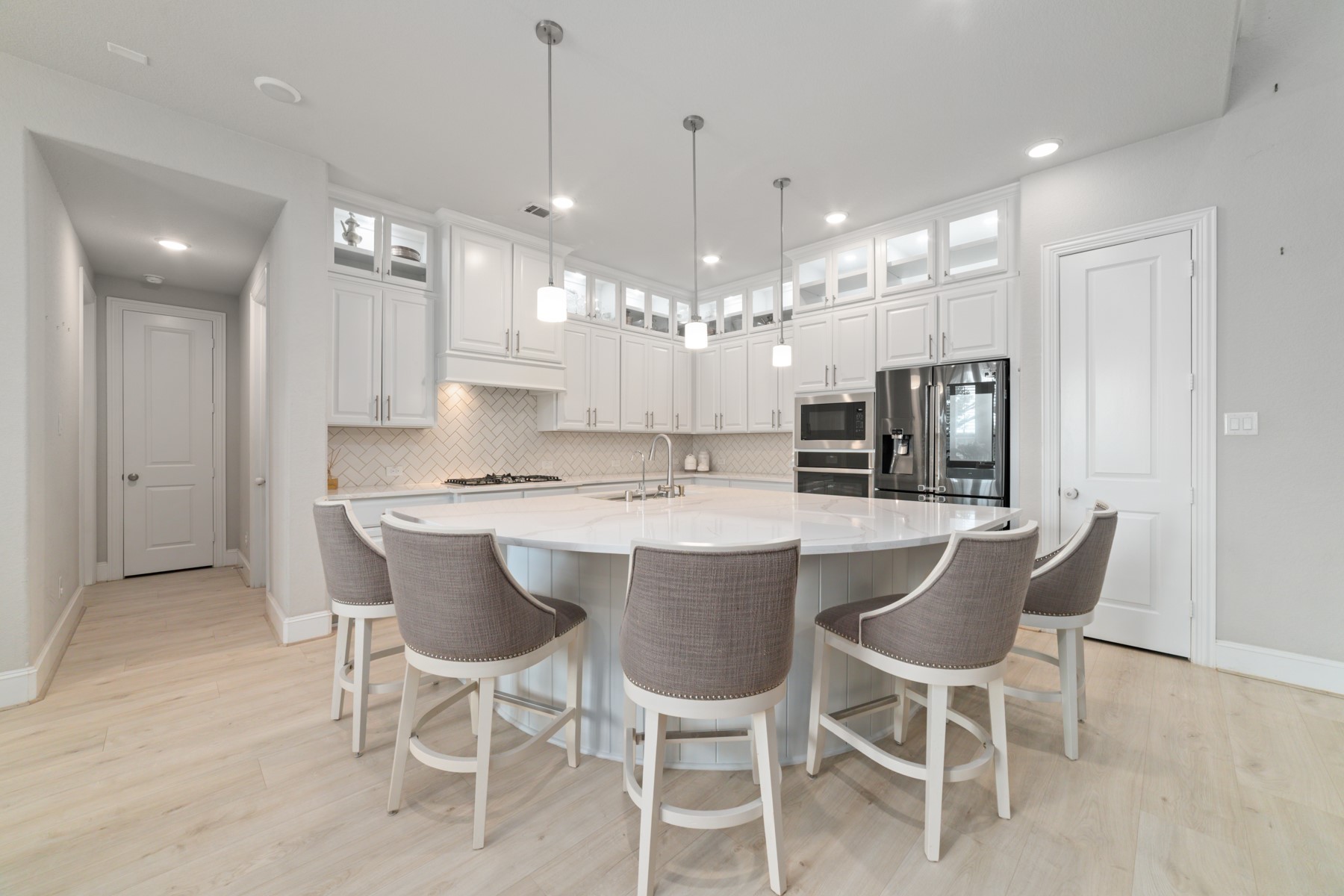 A spacious island with seating, and modern pendant lighting.