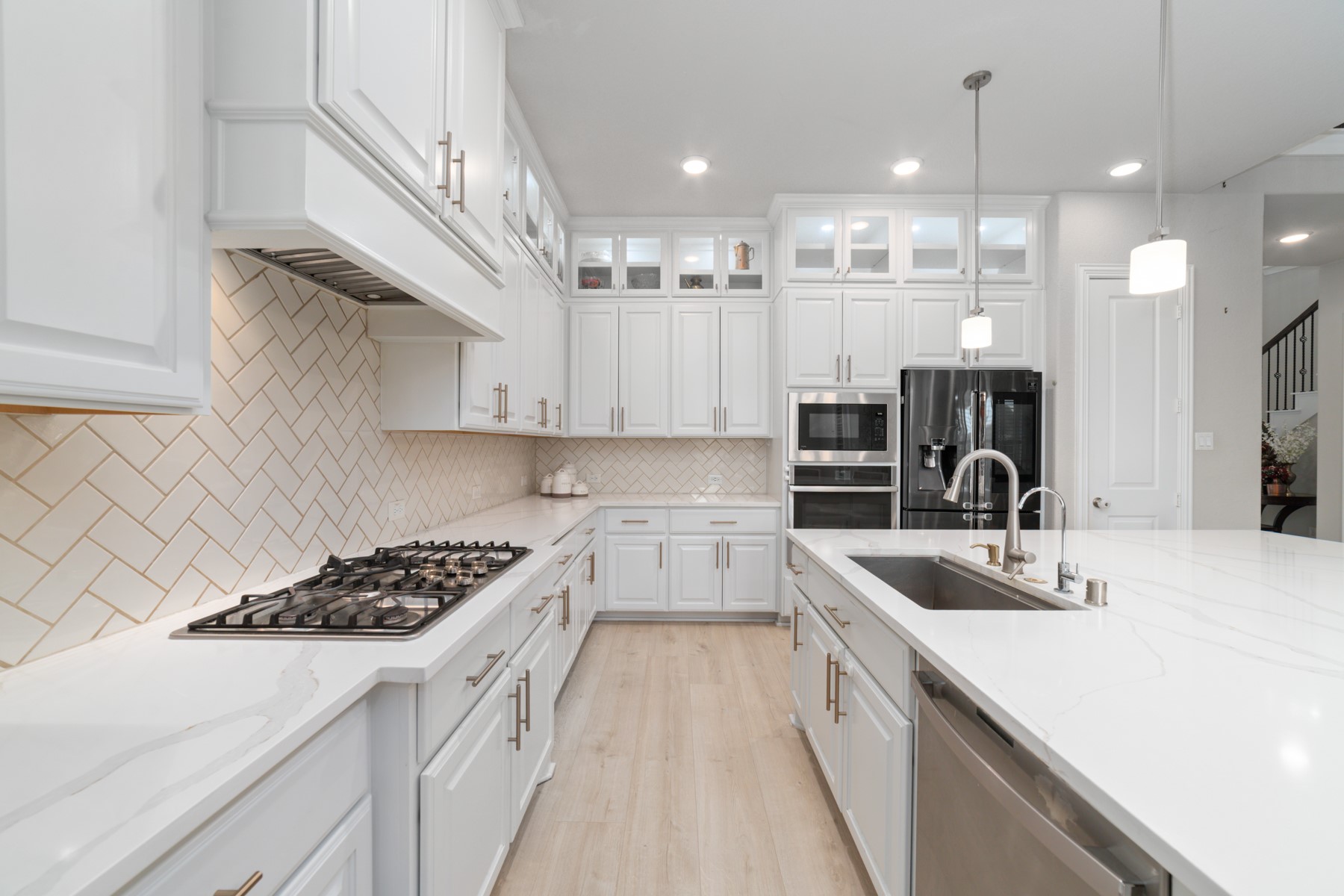 Sleek and modern kitchen featuring crisp white cabinetry, and a spacious island with double sinks.
