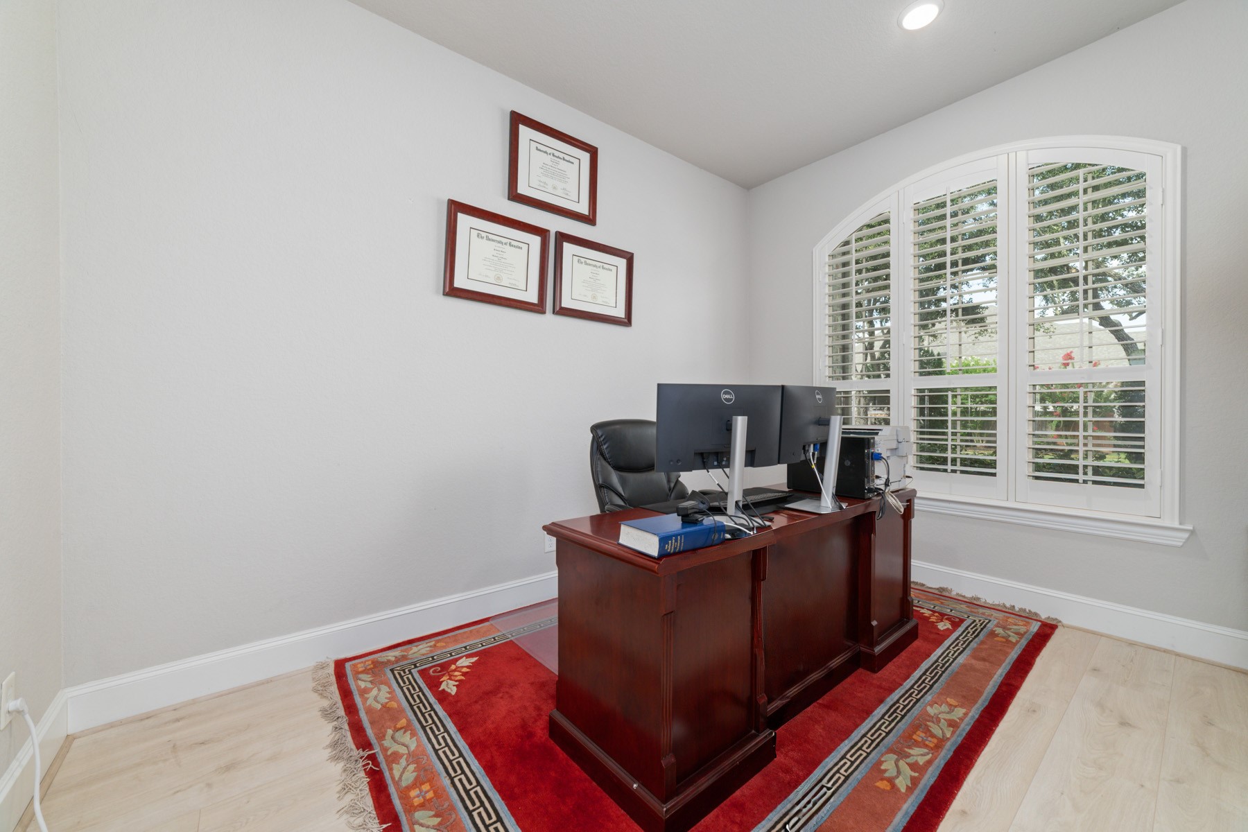 Bright and inviting home office featuring large arched window for natural light.