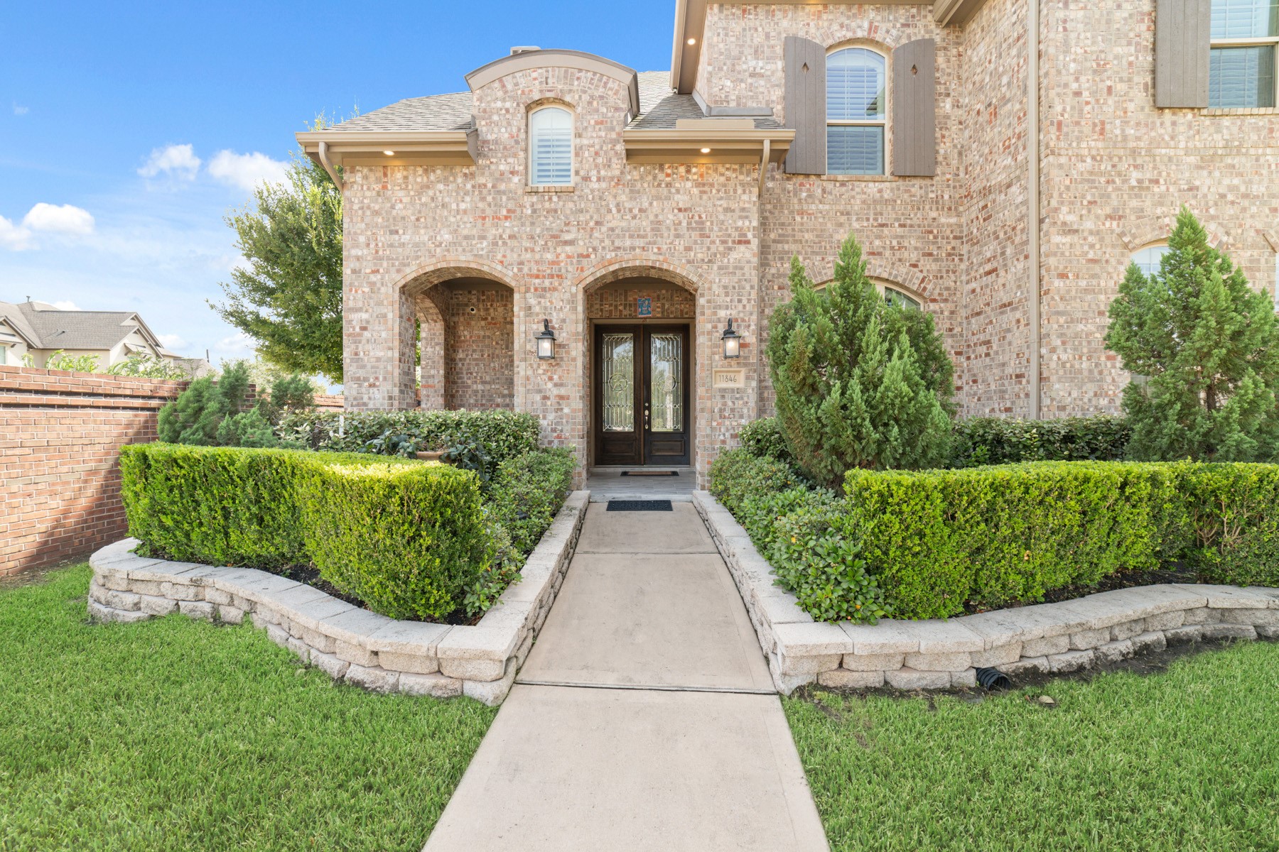 The exterior is framed by manicured hedges and lush greenery.
