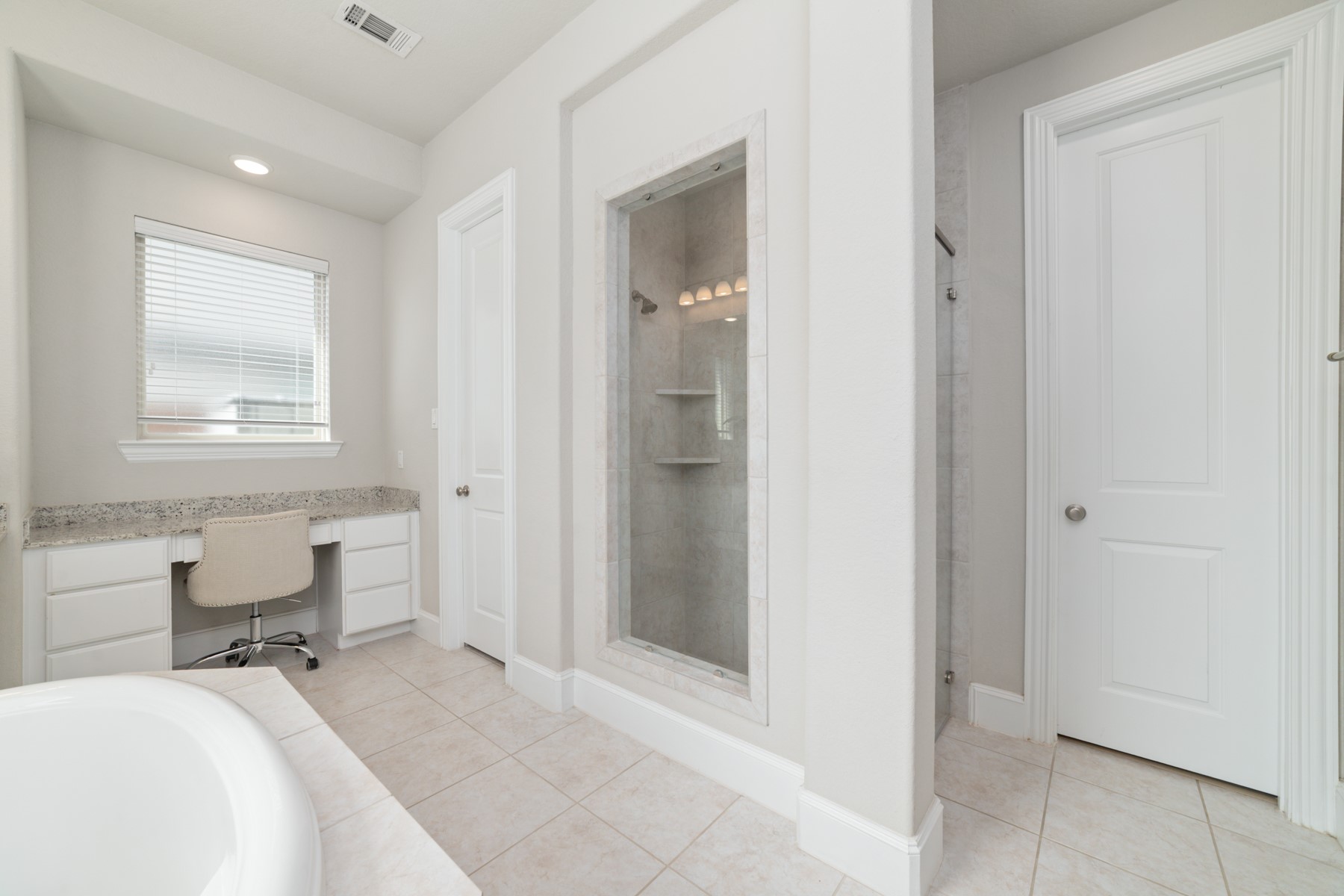 Bright and spacious bathroom featuring a sleek walk-in shower, elegant tiled flooring, and a convenient built-in vanity.