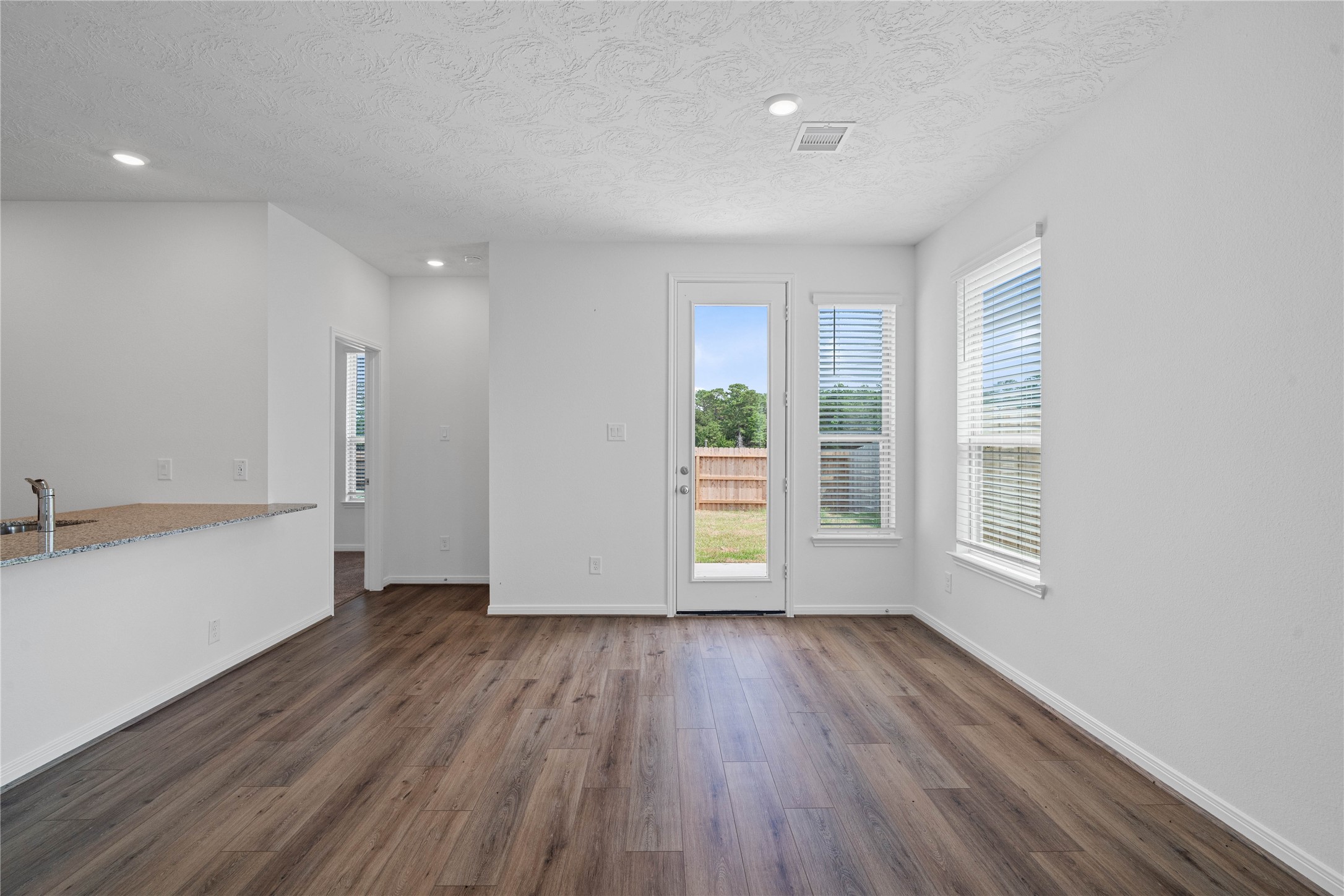 Create lasting memories around the table with family and friends in this inviting dining room! It showcases high ceilings, large window, vinyl plank flooring, recessed lighting, and access door to the backyard. Additionally, there is extra seating with the added breakfast bar to the kitchen granite countertop.