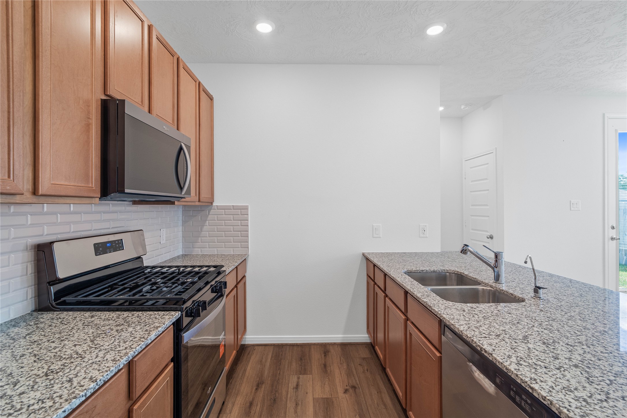 The kitchen features high ceilings, recessed lighting, Woodmont Cody cabinets in Toffee stain, granite countertops in Iberian White, SS appliances including microwave, and a pantry all overlooking your huge Great Room.