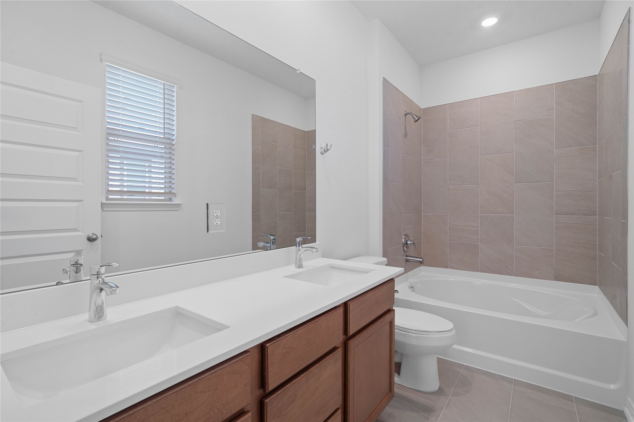 This primary bathroom is definitely move-in ready! Featuring stained cabinets with light countertops, dual vanities, tub/shower combination with tile surround, all with sleek and modern finishes.