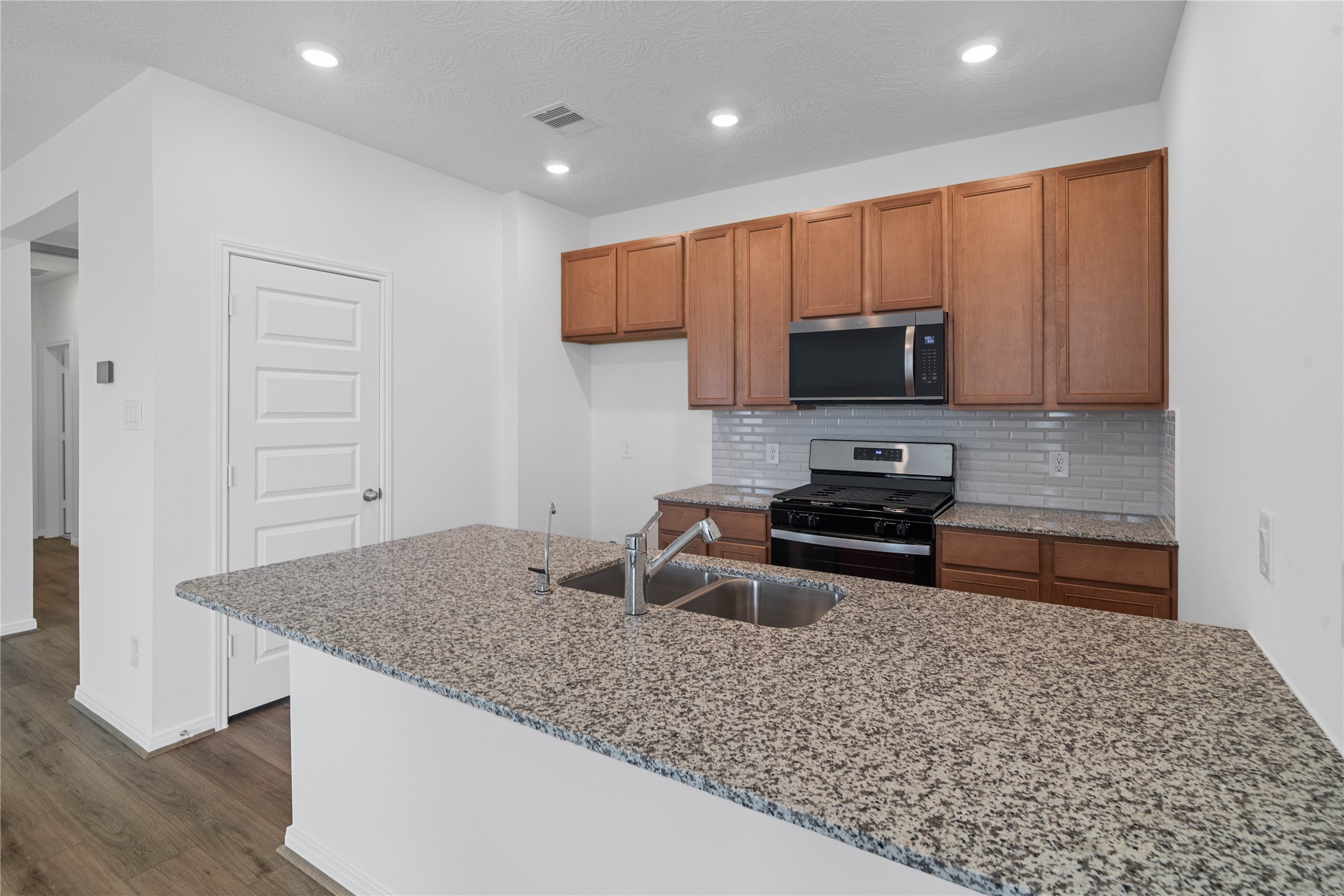 The kitchen exudes warmth with stunning Iberian White granite countertops perfectly paired with the rich, inviting tone of the Woodmont cabinetry in a Toffee stain. This combination creates a truly gorgeous and cohesive aesthetic.