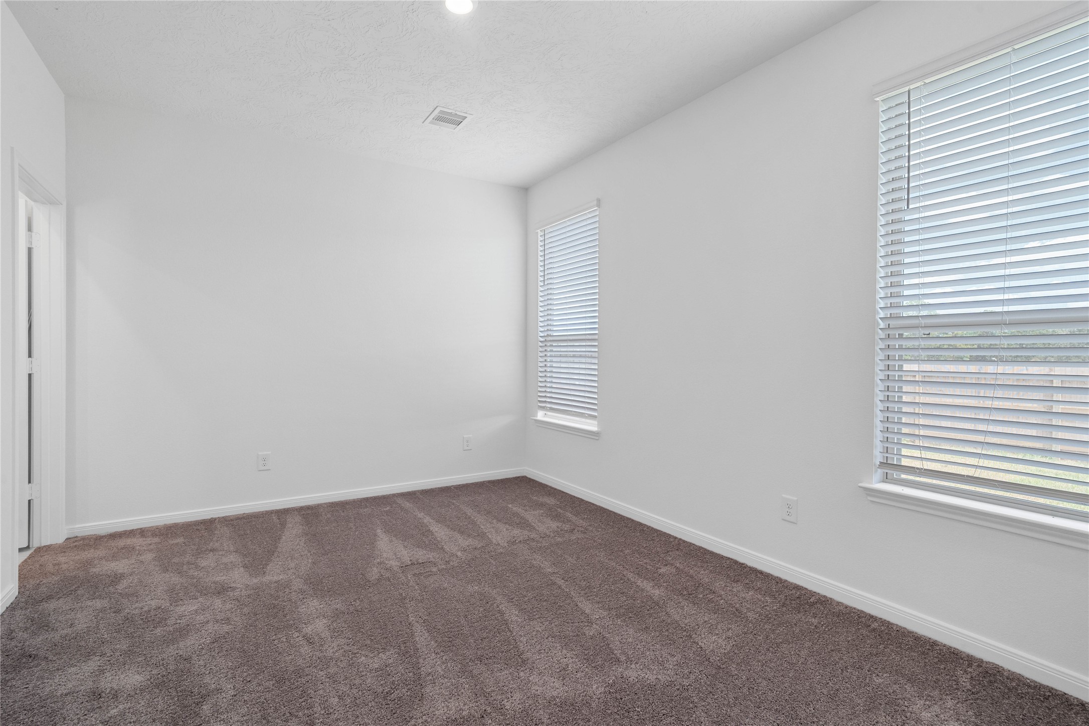 Come and unwind after a long day in this magnificent primary suite! This spacious room features plush carpet flooring, neutral paint, high ceilings, recessed lighting, and large windows fitted with blinds!