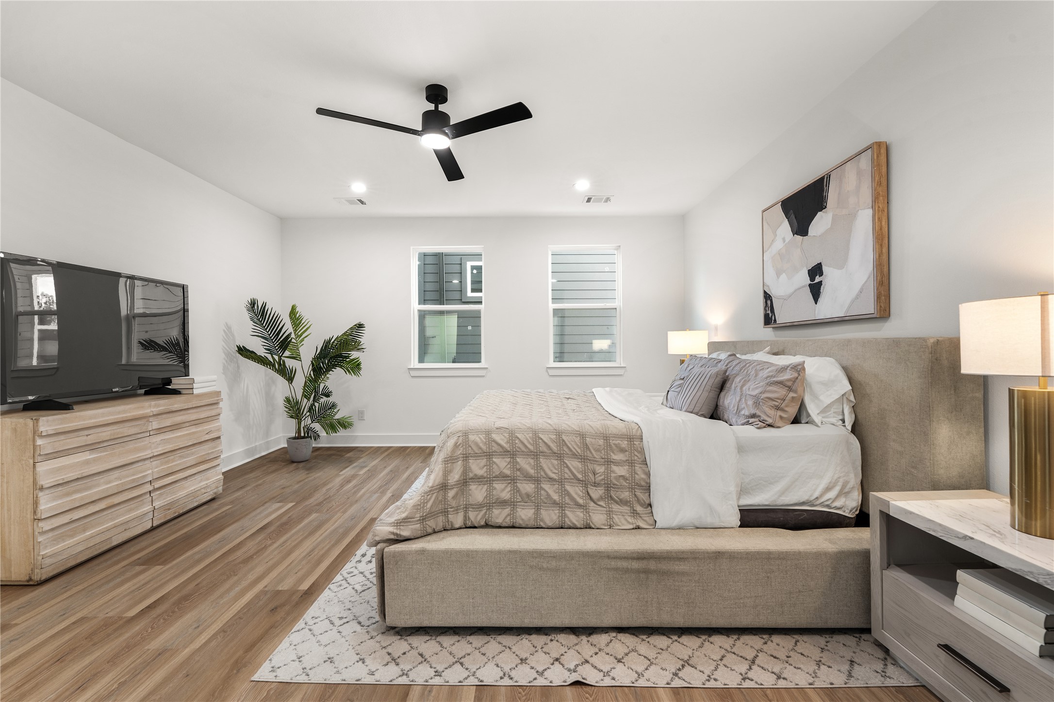 The primary suite is designed as a true retreat, pairing open, airy proportions with recessed lighting, a
matte-black ceiling fan, and warm wide-plank flooring.