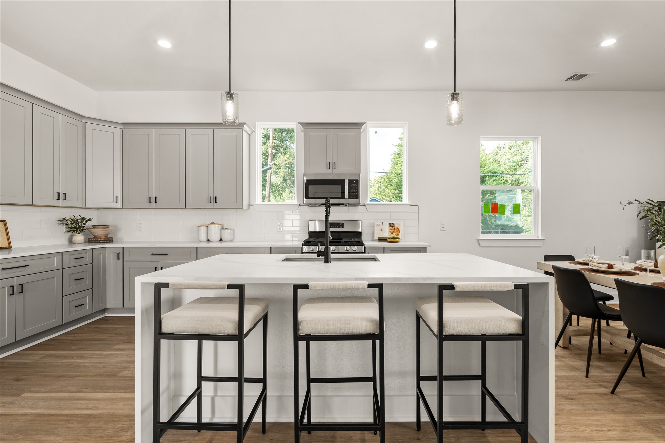 A pair of windows frames the range wall in balance, while the island's integrated sink and matte-black
pull-down faucet keep prep work centered and connected to the rest of the room.