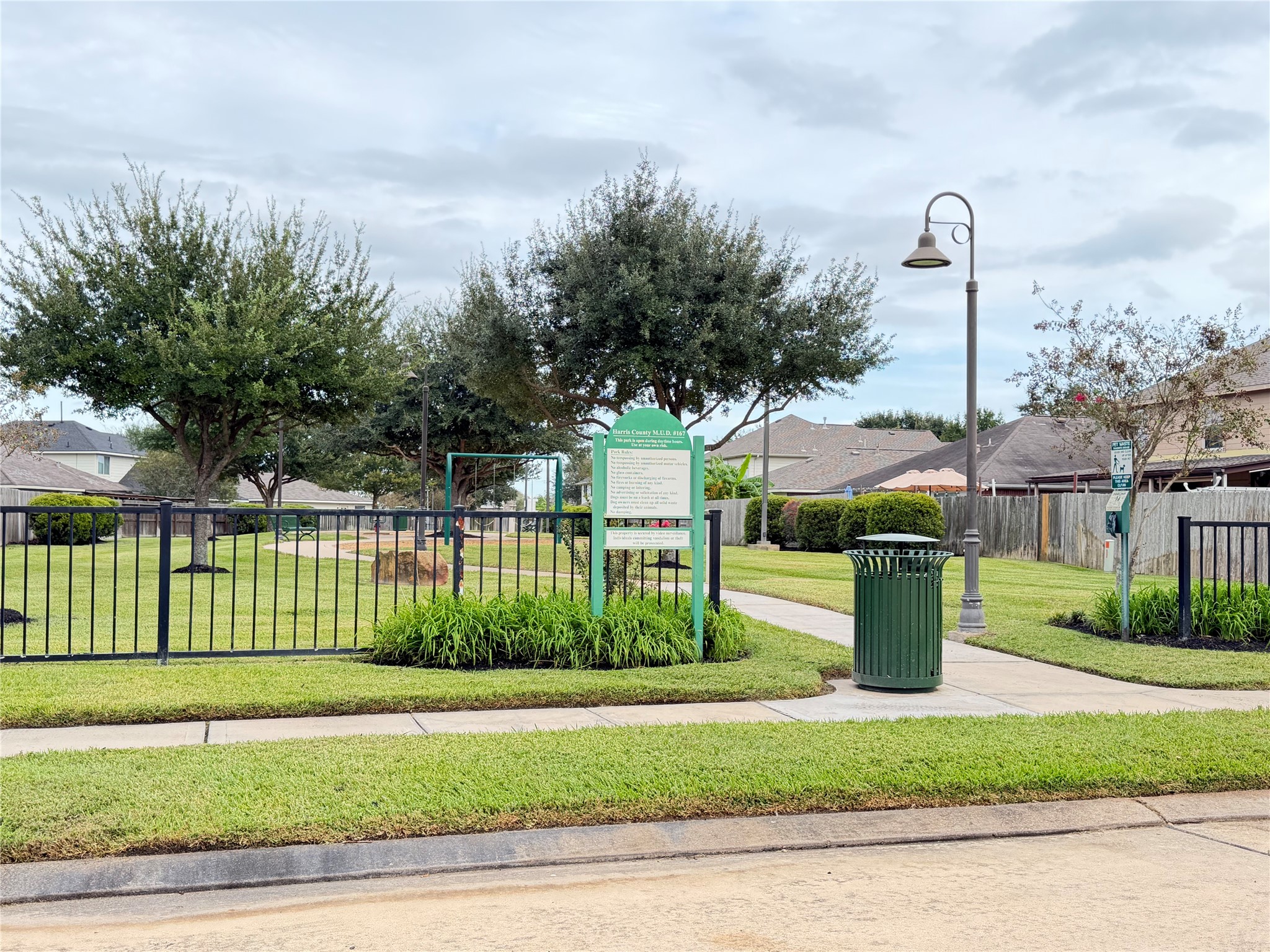 Charming community park with lush greenery, mature trees, and a welcoming pathway, nestled within a serene neighborhood.