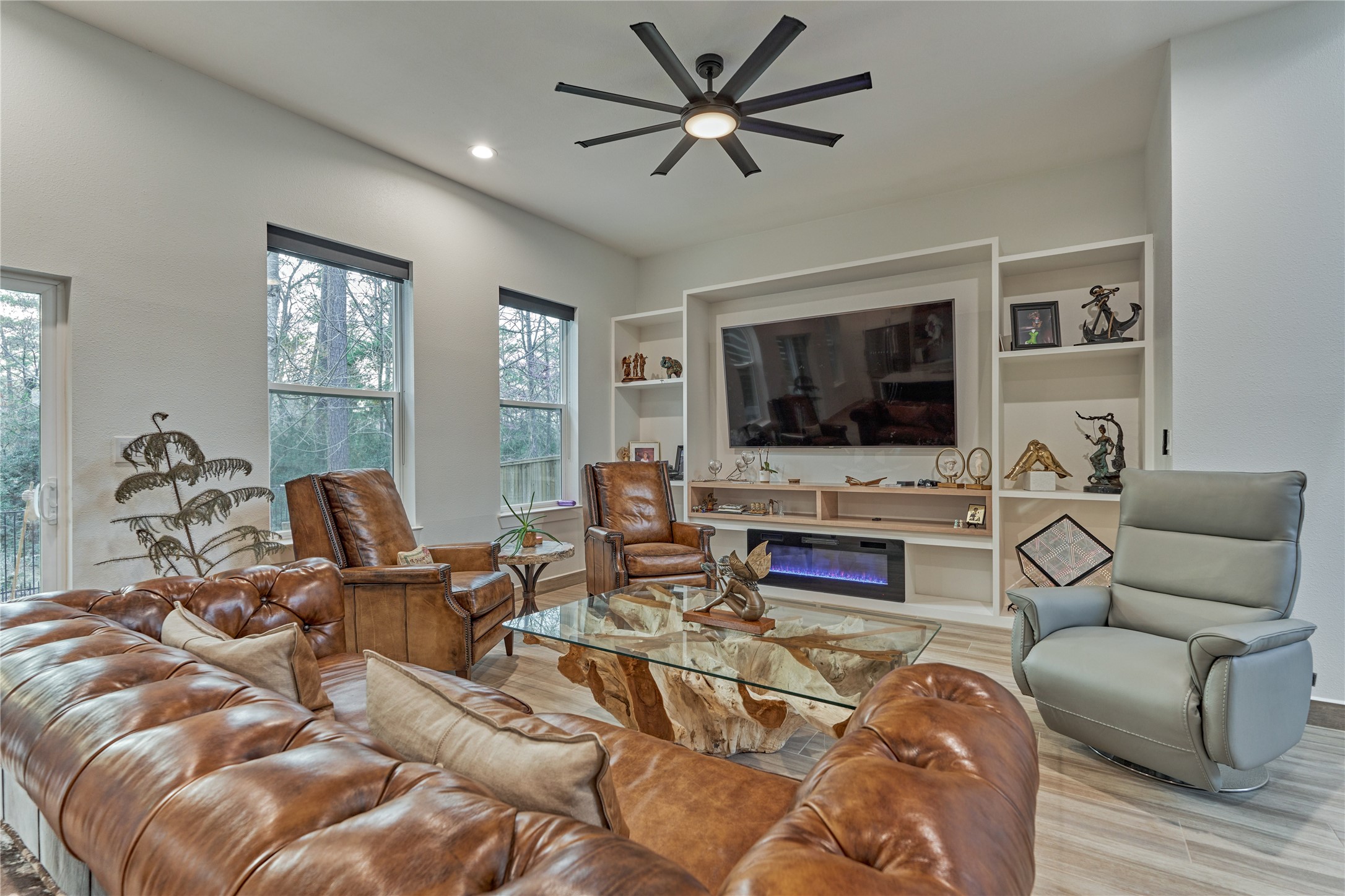 The open and inviting living room features an entertainment wall and enjoys serene views of the backyard. An electric (mock) fireplace adds cozy ambiance, perfect for relaxing evenings.