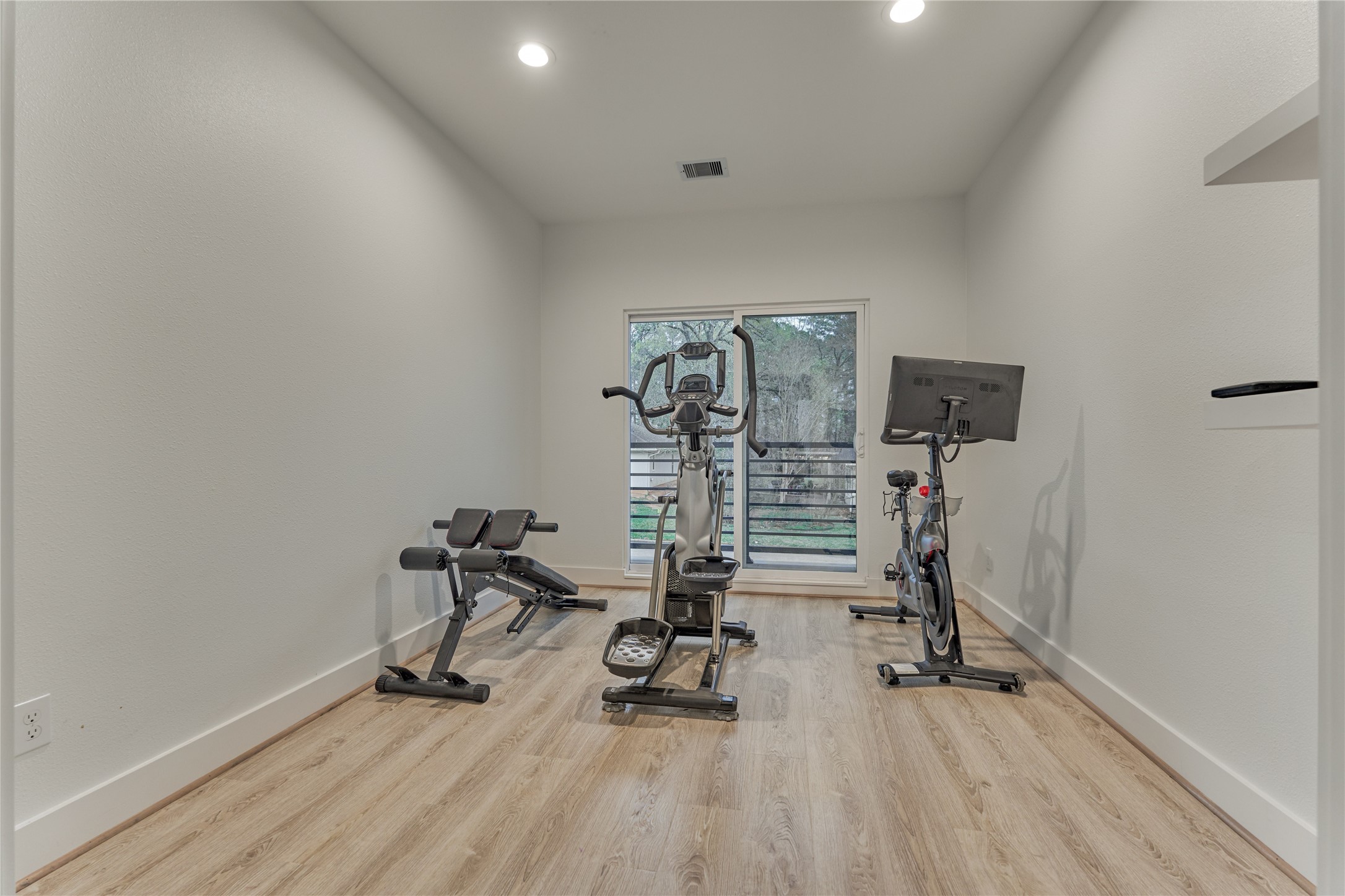 Home office with access to a private outdoor balcony. Currently used as a home gym, this versatile space could easily serve as a study, hobby room, or additional flex space.