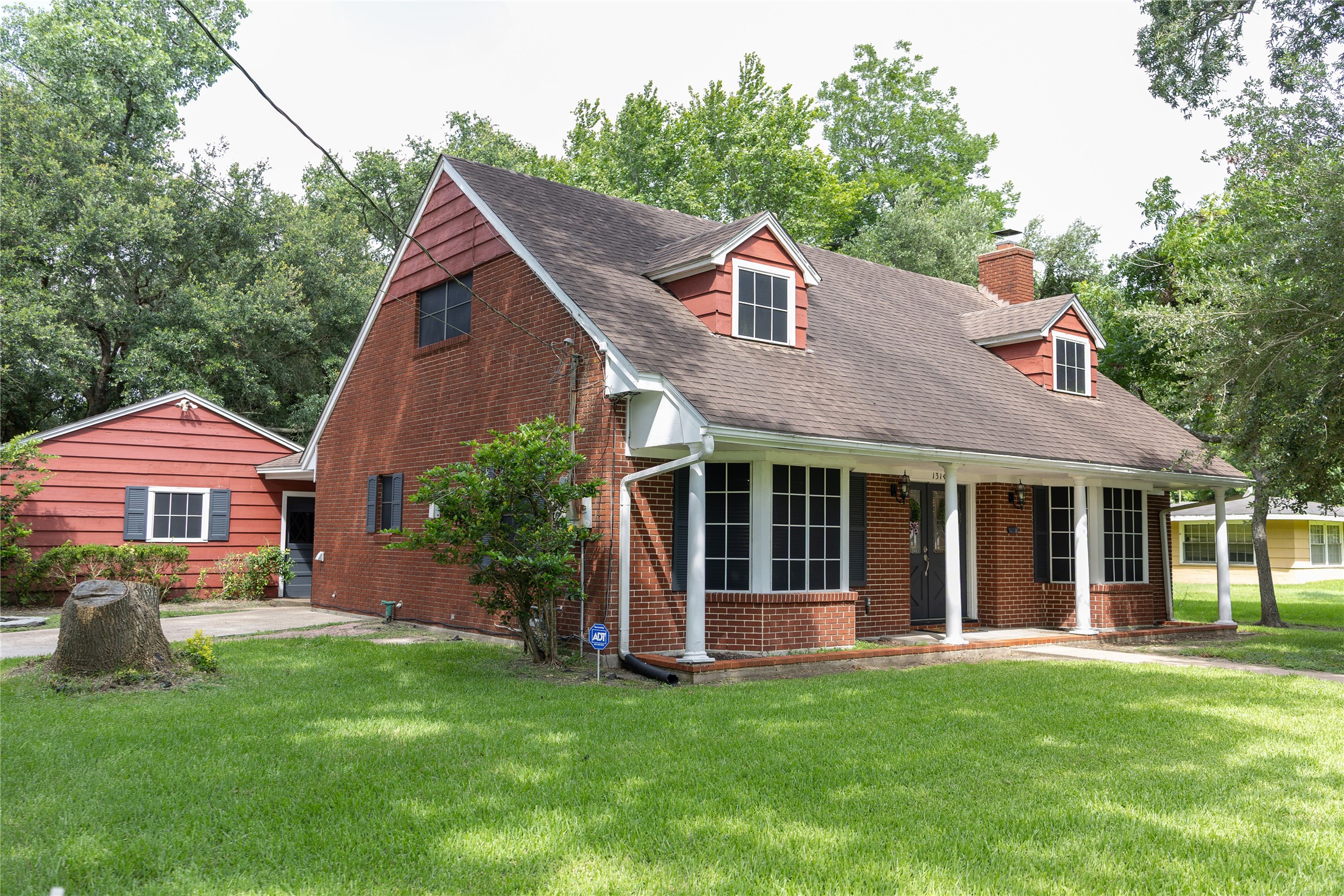 1314 Laurel features a spacious front porch, mature trees, and a well-maintained lawn, offering a welcoming and serene atmosphere.