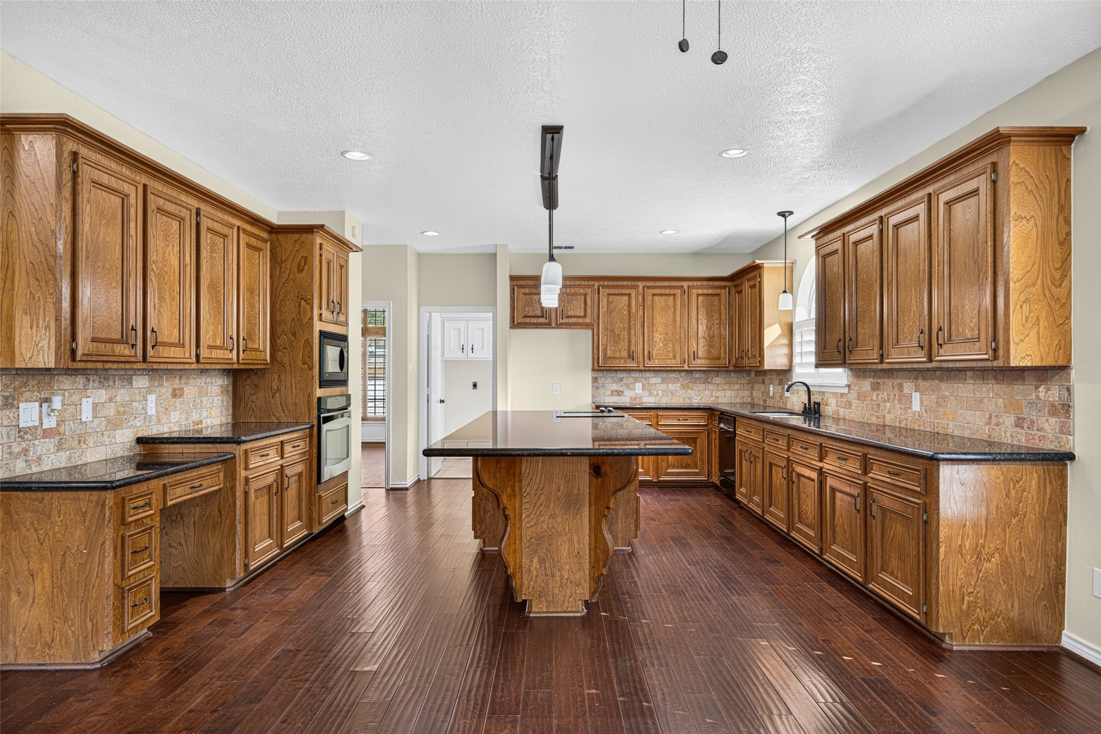 The spacious kitchen features rich wood cabinetry, granite countertops, and an expansive island.