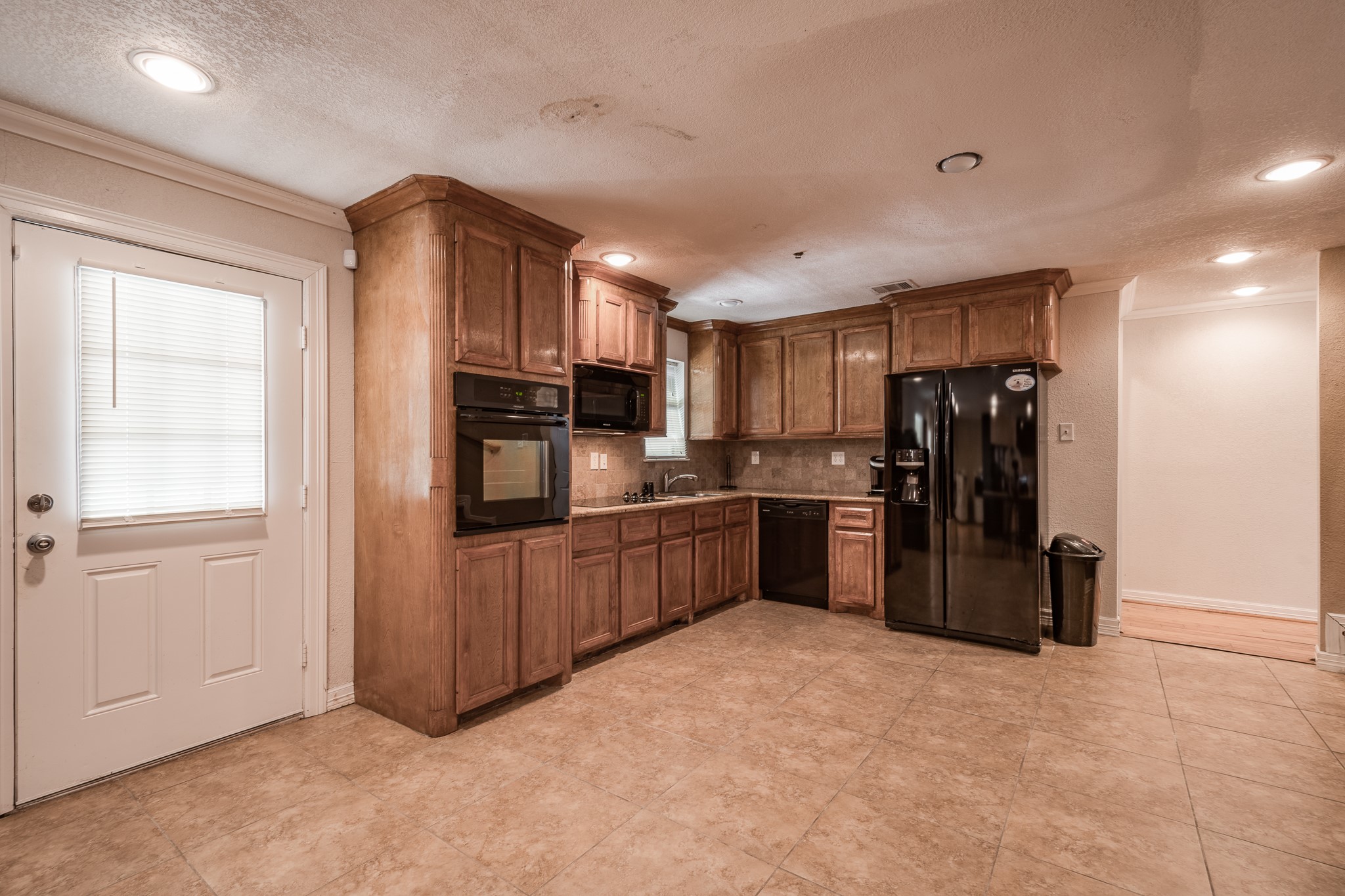 Spacious kitchen featuring rich wooden cabinetry, modern appliances, and ample natural light from the adjacent door, creating a warm and inviting atmosphere. Spacious kitchen featuring rich wooden cabinetry, modern appliances, and ample natural light from the adjacent door, creating a warm and inviting atmosphere.