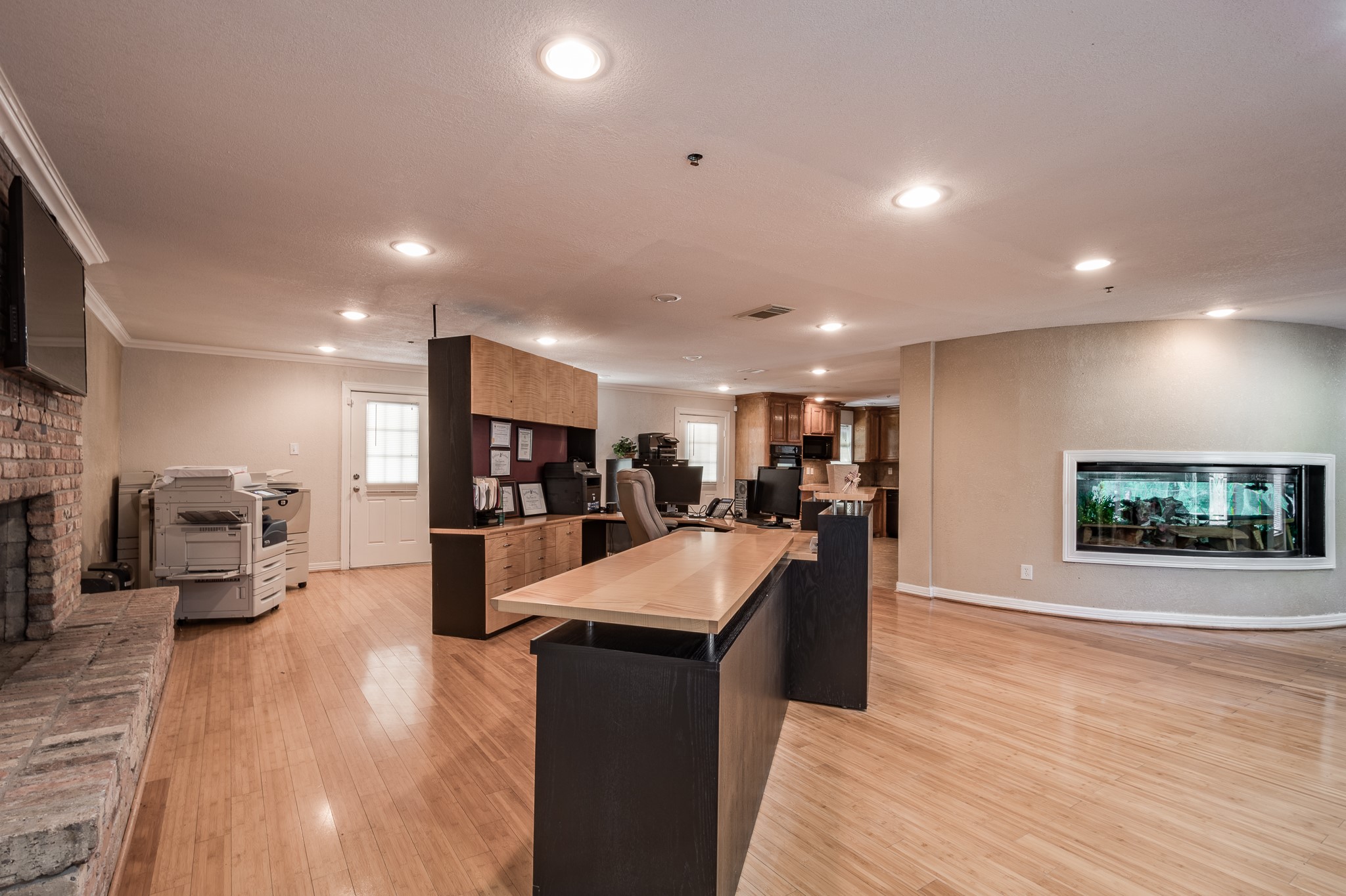 Spacious home office with sleek wood flooring, built-in desk, and a cozy brick fireplace, perfect for work and relaxation. Spacious home office with sleek wood flooring, built-in desk, and a cozy brick fireplace, perfect for work and relaxation.