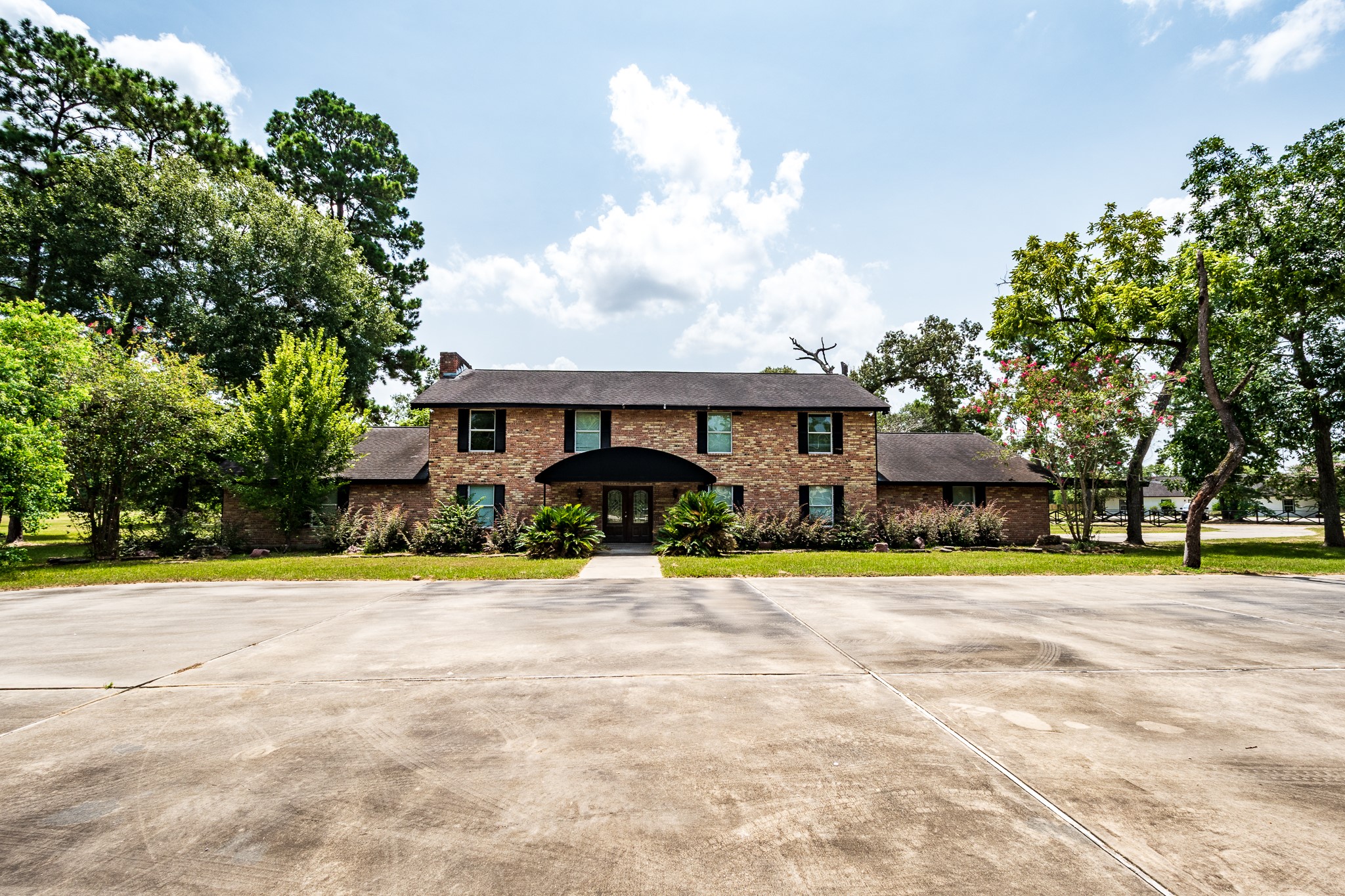 Stately two-story brick home surrounded by mature trees, featuring a spacious driveway and a welcoming entrance. Stately two-story brick home surrounded by mature trees, featuring a spacious driveway and a welcoming entrance.