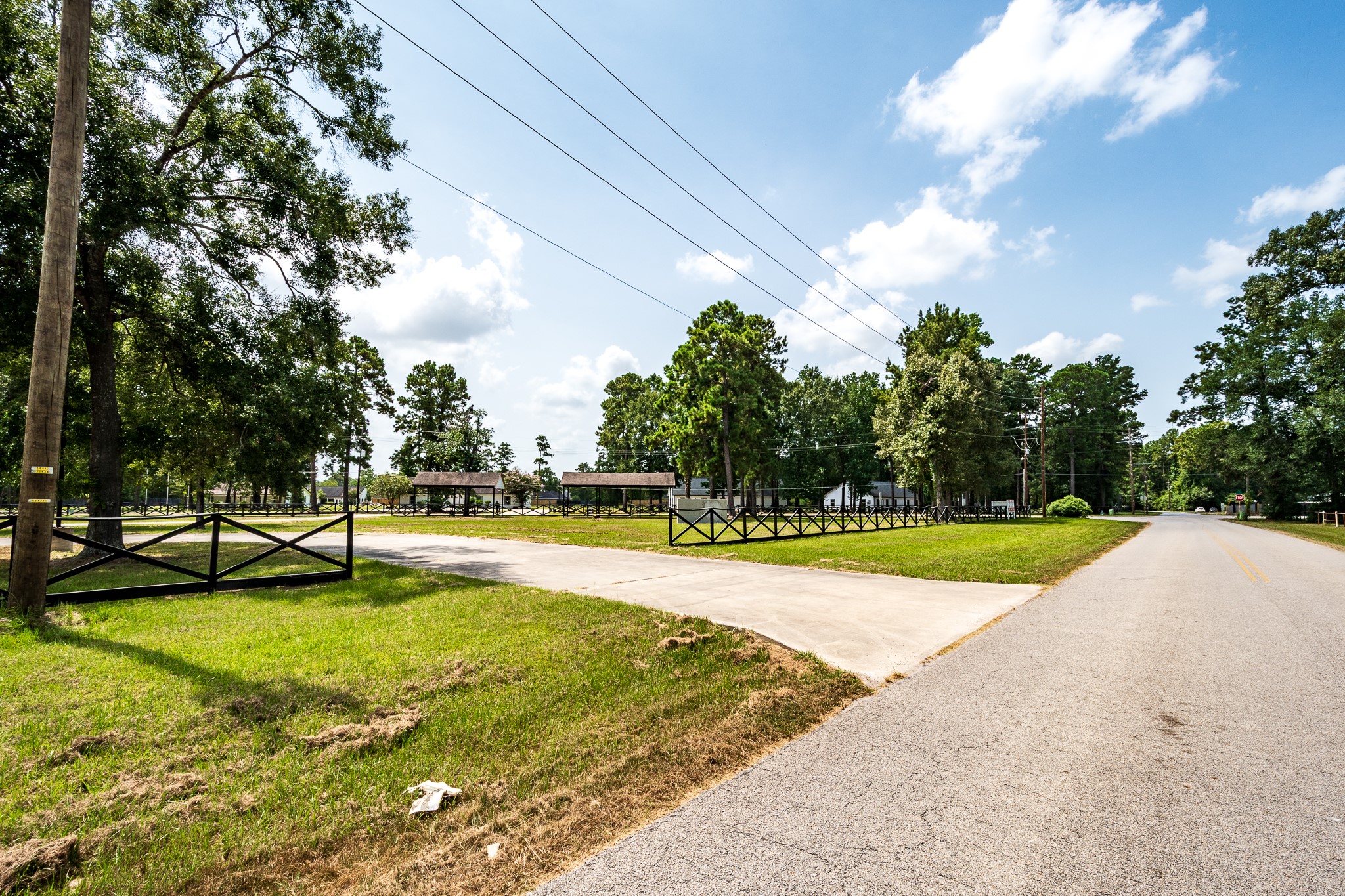 Expansive lot with a charming fence and mature trees, offering a serene setting along a quiet road.