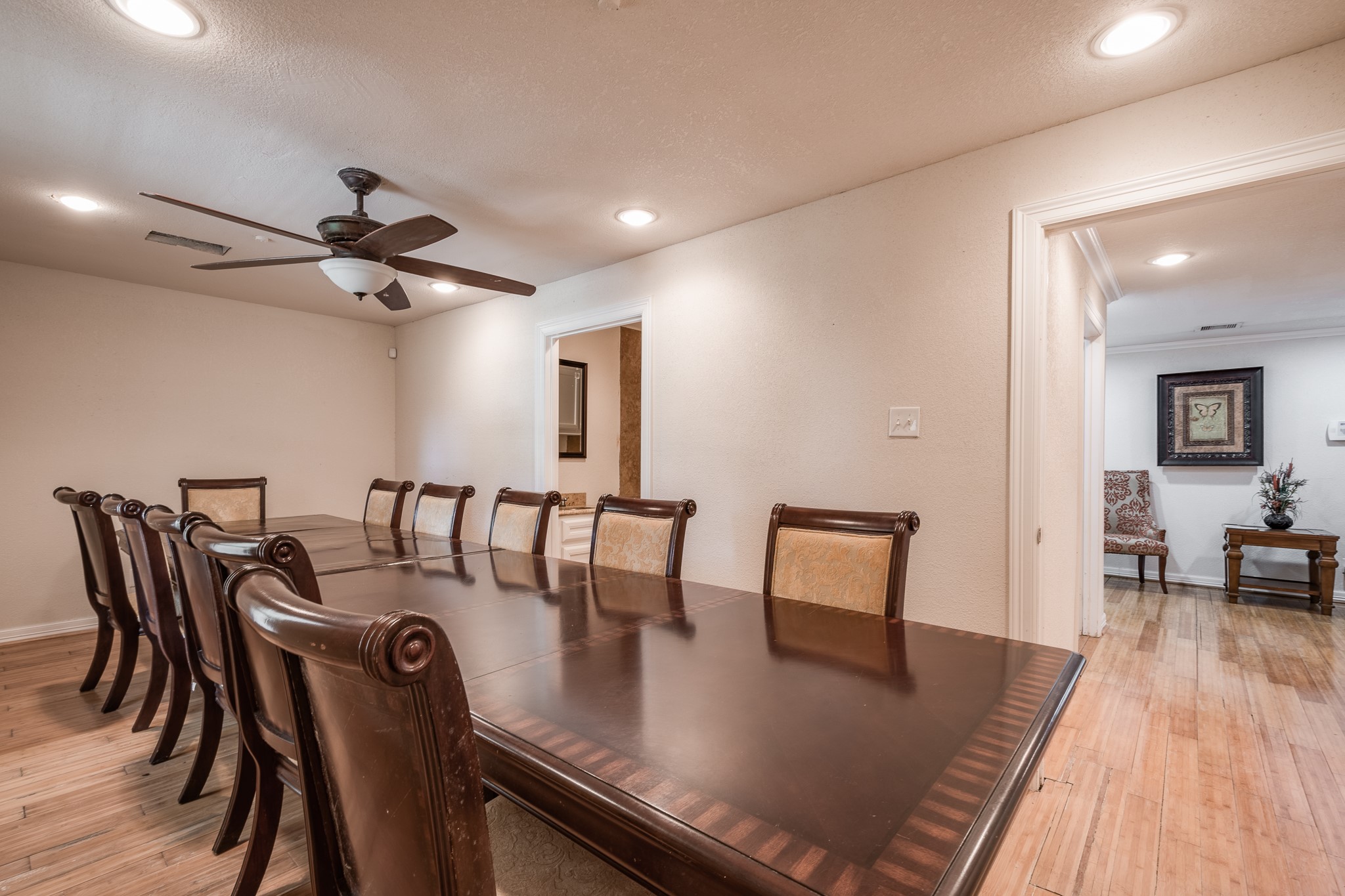 Elegant dining room with a spacious table for ten, highlighted by warm wood flooring and recessed lighting, perfect for gatherings. Elegant dining room with a spacious table for ten, highlighted by warm wood flooring and recessed lighting, perfect for gatherings.