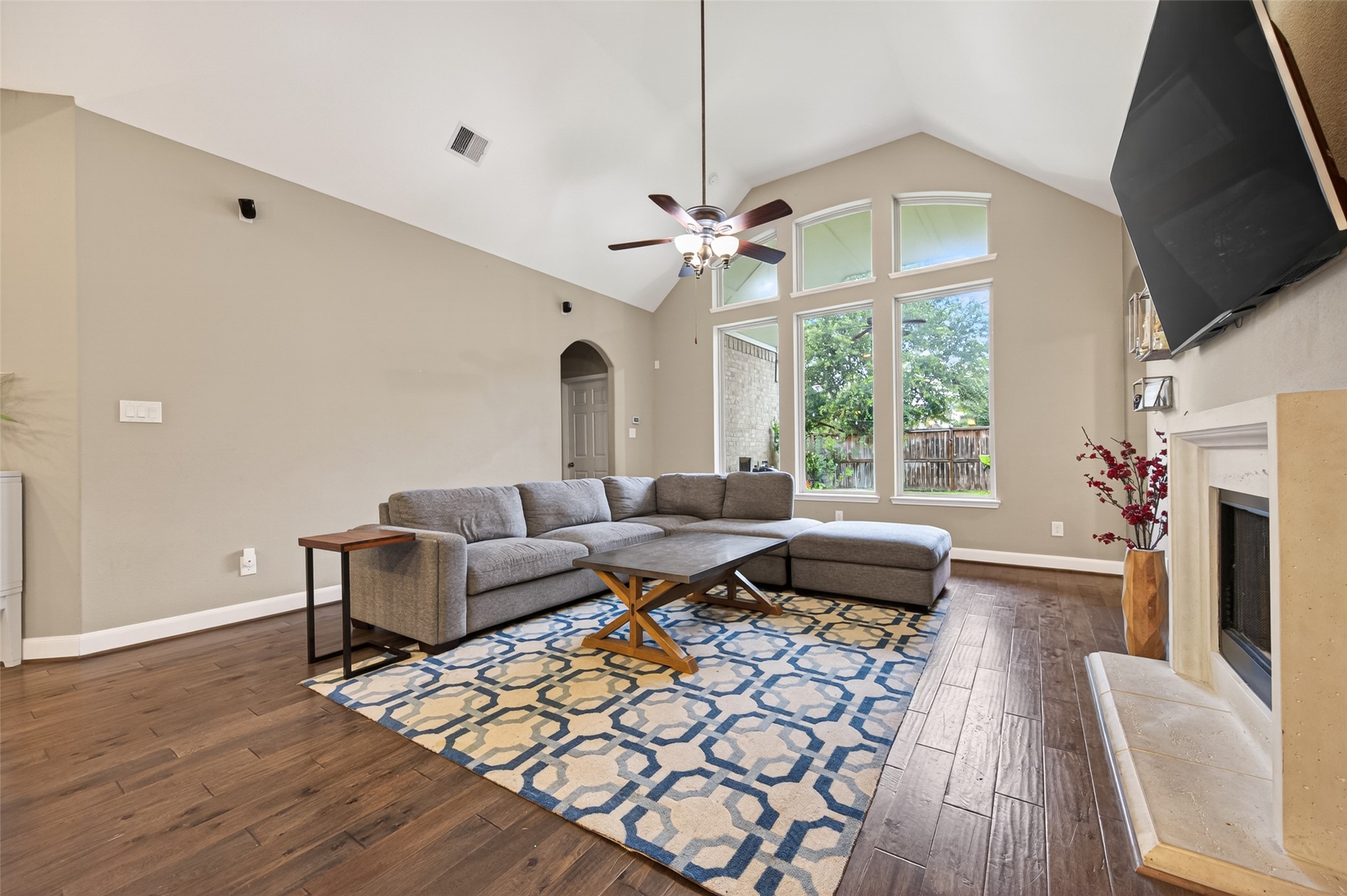 High vaulted ceiling opens up the space welcoming natural light from the tall windows looking out to the covered patio