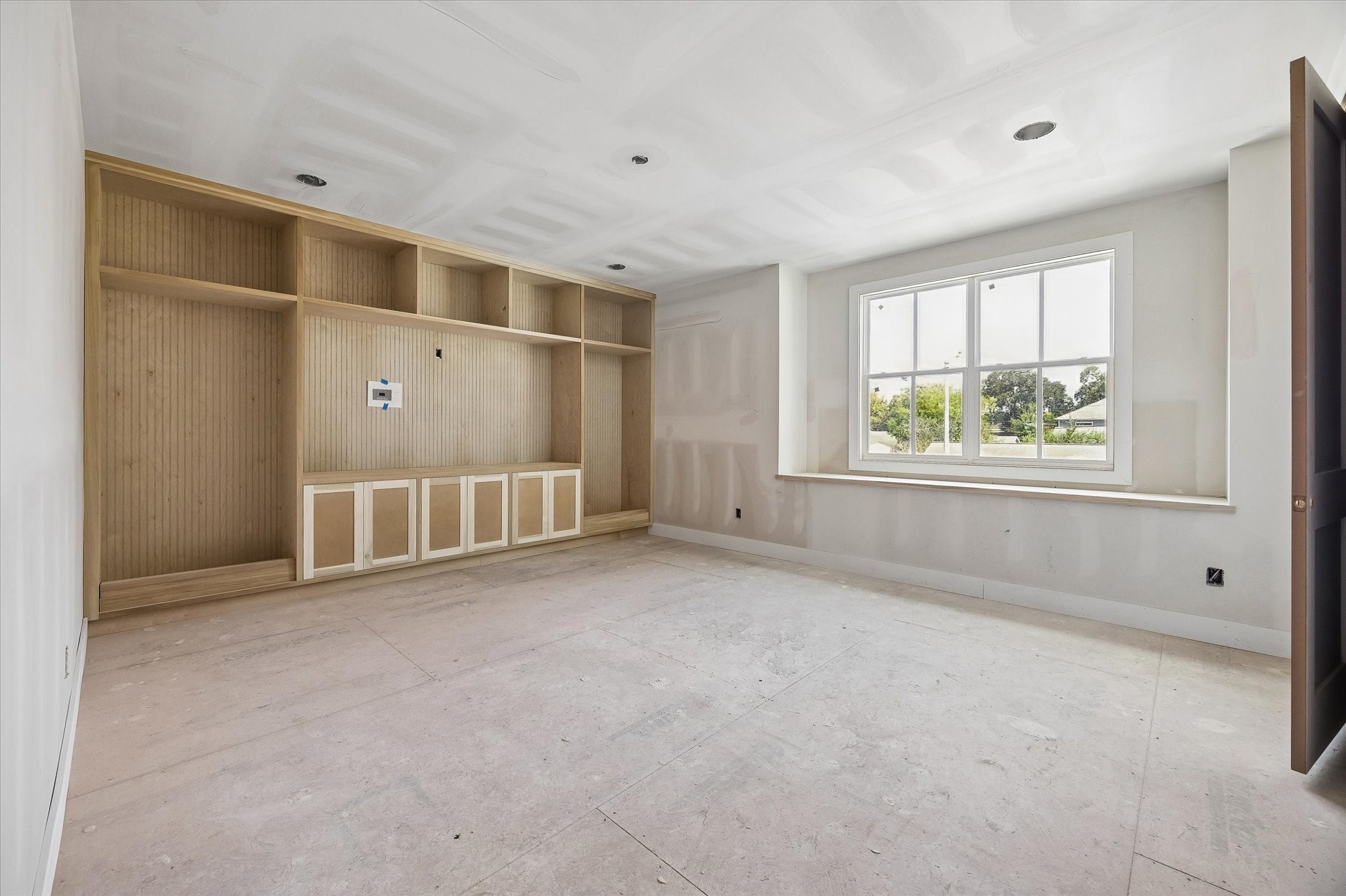 Designed for everyday downtime, the spacious game room features a full wall of custom built ins with fluted wood detailing and integrated storage. A large window brings in natural light while leaving plenty of open space for games, media and lounging. **Current Construction as of 9/11/26