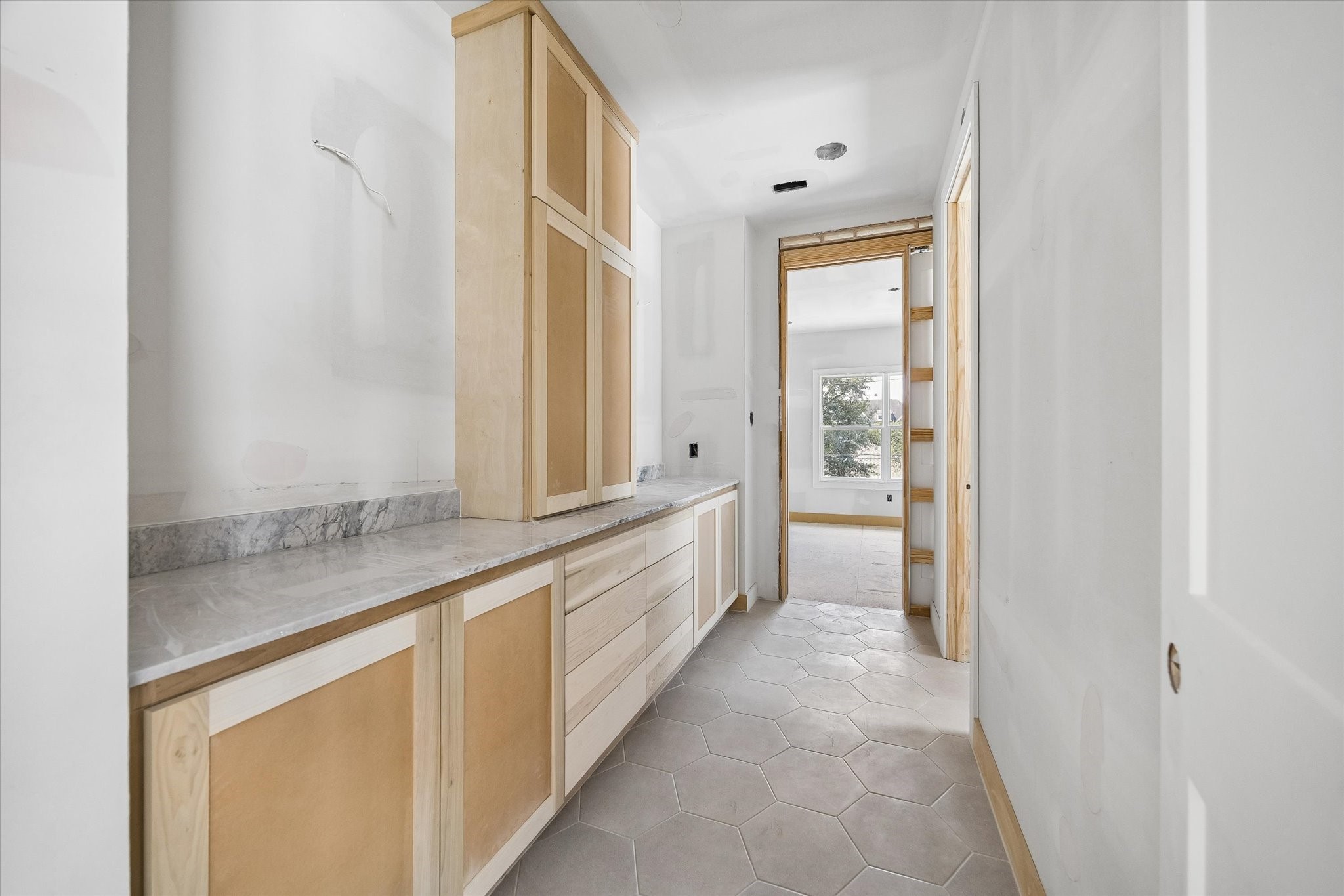 Jack and Jill bath connects the secondary bedrooms with an elongated vanity, generous cabinetry and stone countertops. Hexagonal floor tile adds subtle dimension while built in storage keeps everyday essentials organized. **Current Construction as of 9/11/26