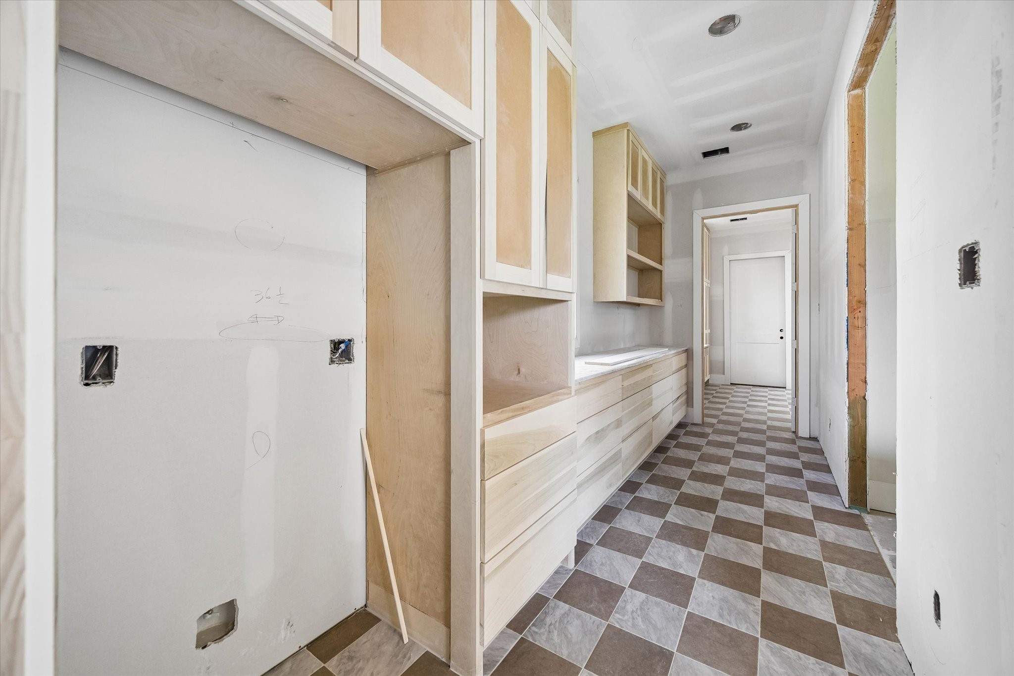 Designed to keep prep and cleanup tucked away from the main kitchen, the spacious scullery offers extensive custom cabinetry, long stretches of counter space, and dedicated appliance zones. Checkerboard flooring brings a distinctive design moment to this hardworking secondary kitchen space. **Current Construction as of 9/11/26