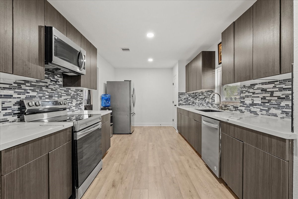 The eye-catching mosaic glass tile backsplash adds a touch of texture and personality, beautifully complementing the kitchens black, white, and gray color palette.