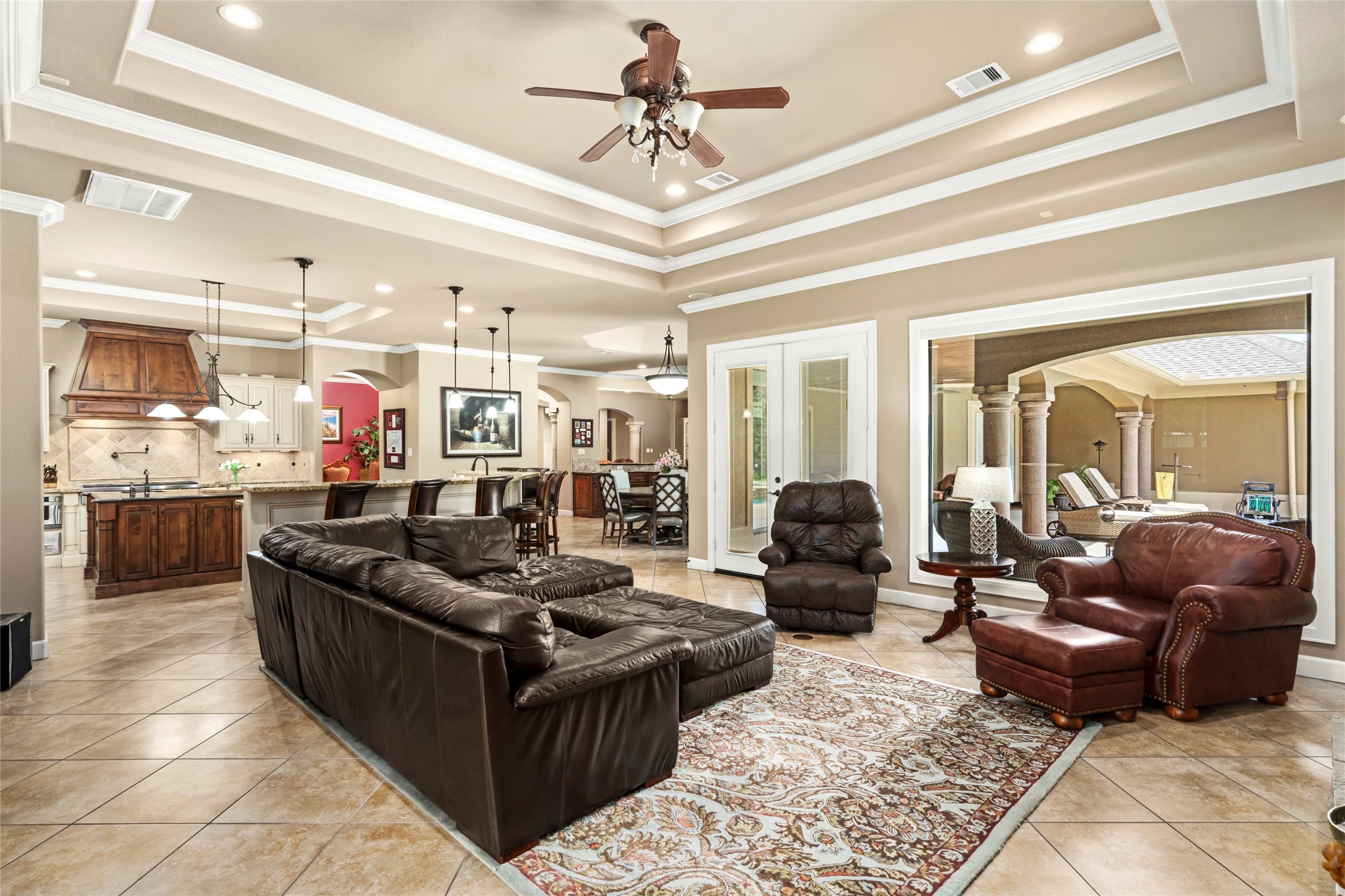 The family room with the wall of glass and the double French doors leading outside. A direct open view into the kitchen.