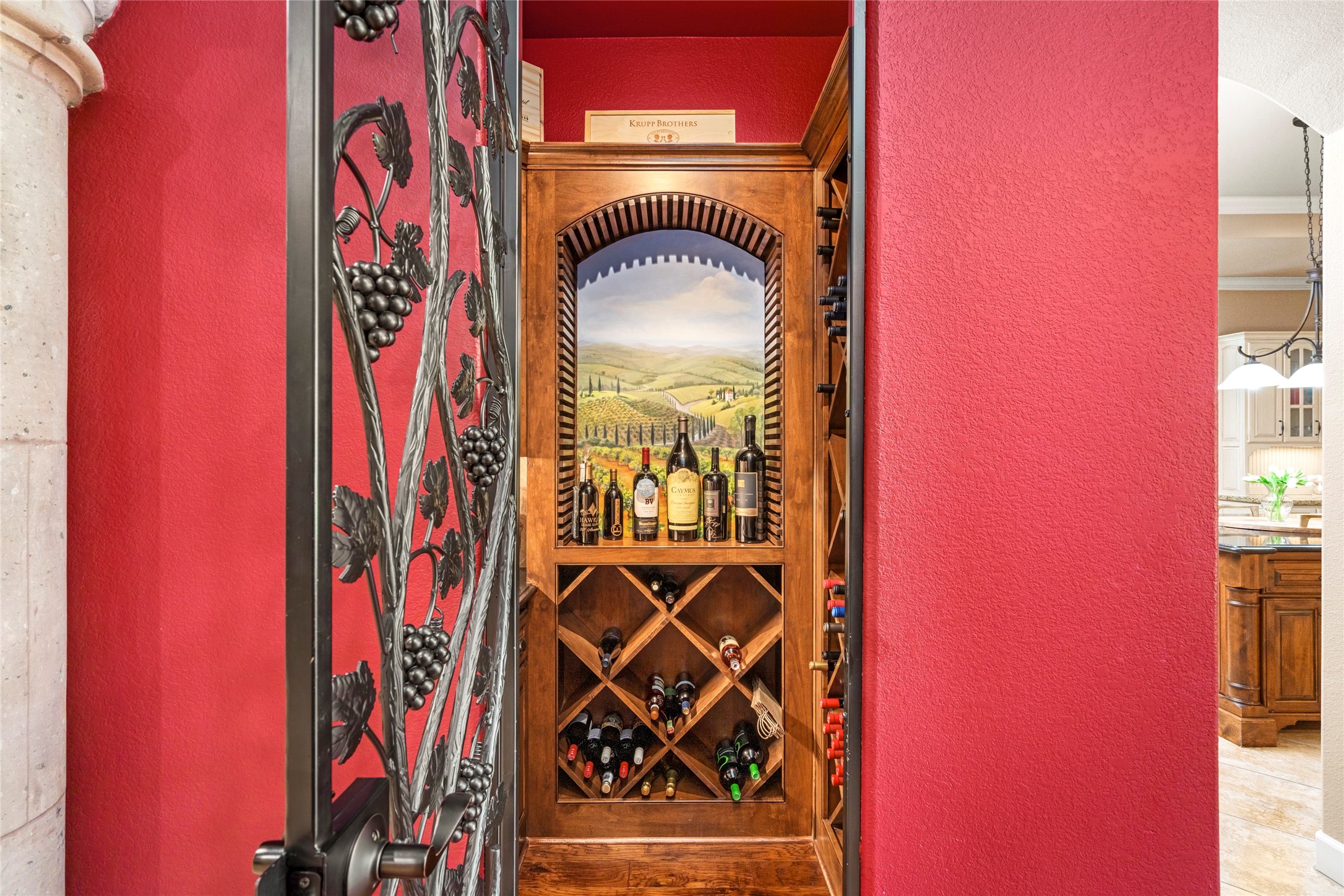 The wine room behind an iron door adorned with grape motifs, offers ample wine storage and evokes the charm of Italy's wine country.