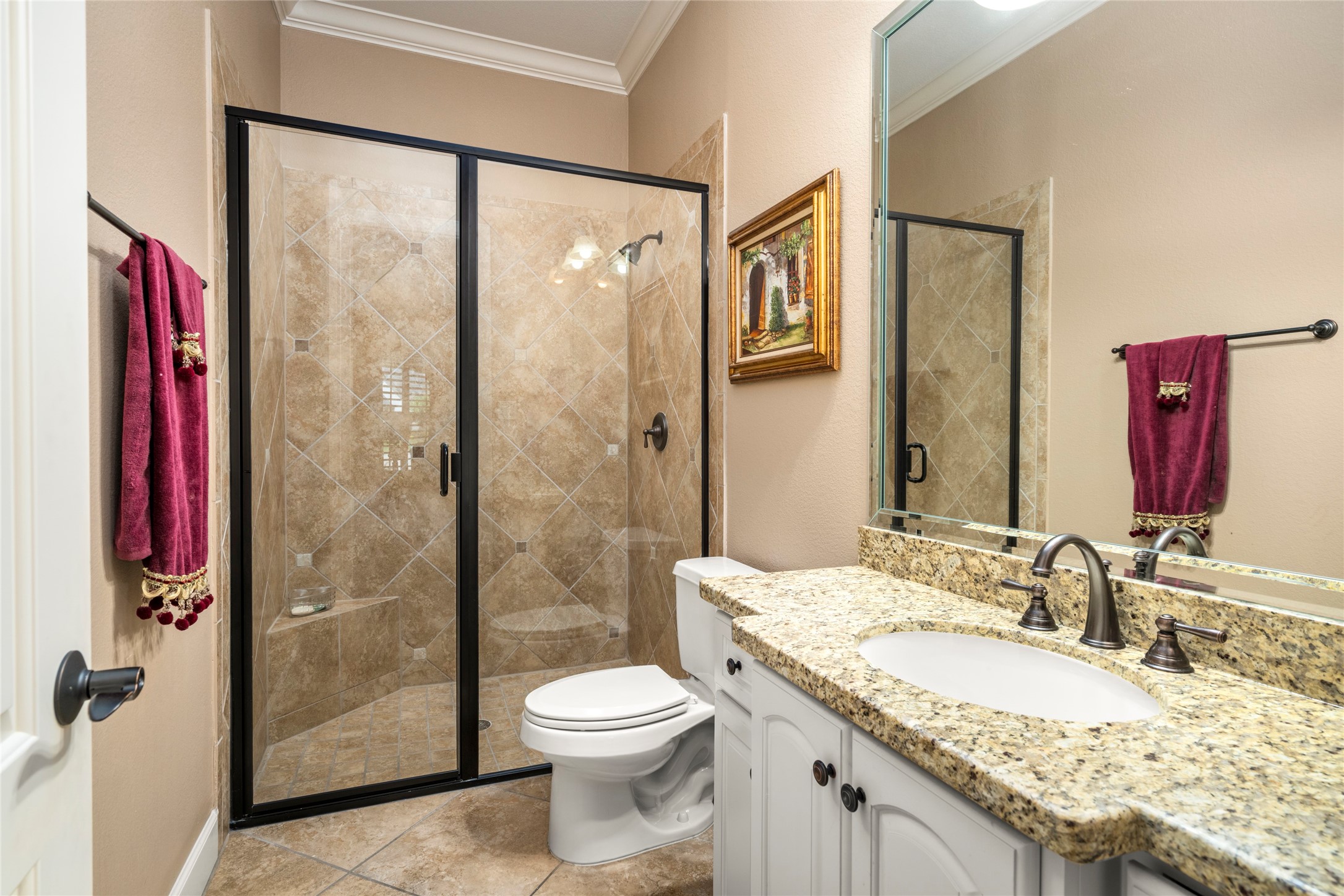 En-suite bathroom offers a walk-in shower, granite countertops, and thoughtful finishes, ideal for this bedroom.