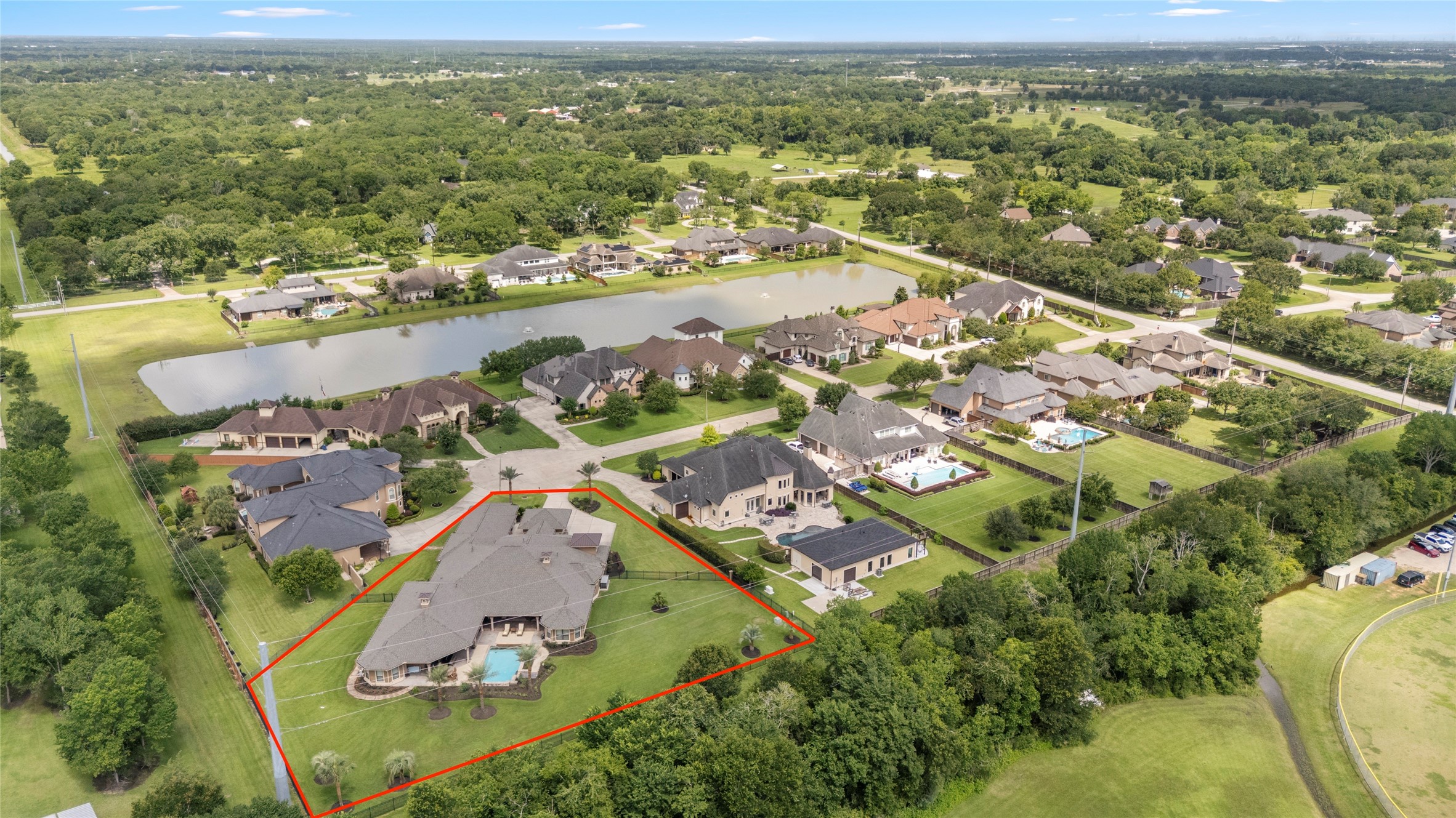 Aerial view of the community capturing the lake a block away, a private backyard framed by mature trees, and a serene outdoor oasis.