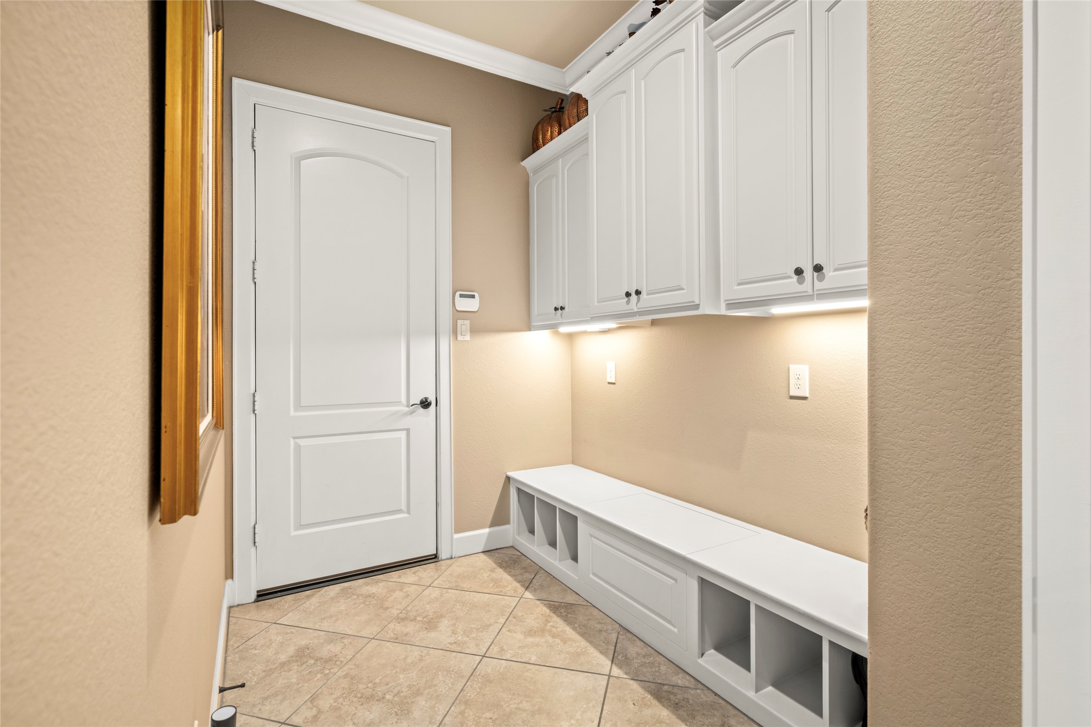 Entering from the garage, a convenient mudroom along the hallway offers built-in storage cabinets and a bench with cubbies, perfect for unloading and organizing as you come home.
