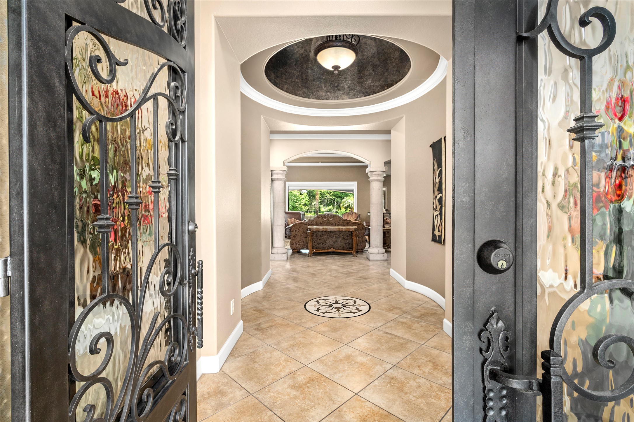 Step through custom designed iron doors with intricate glass and metal detailing. The foyer greets you with rounded ceilings and intricate millwork.