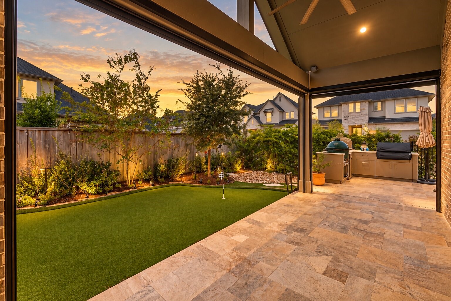Evening on the covered back patio, where recessed lighting and a tiled floor open onto a level, fenced lawn - an easy spot for morning coffee or for entertaining friends after sunset.