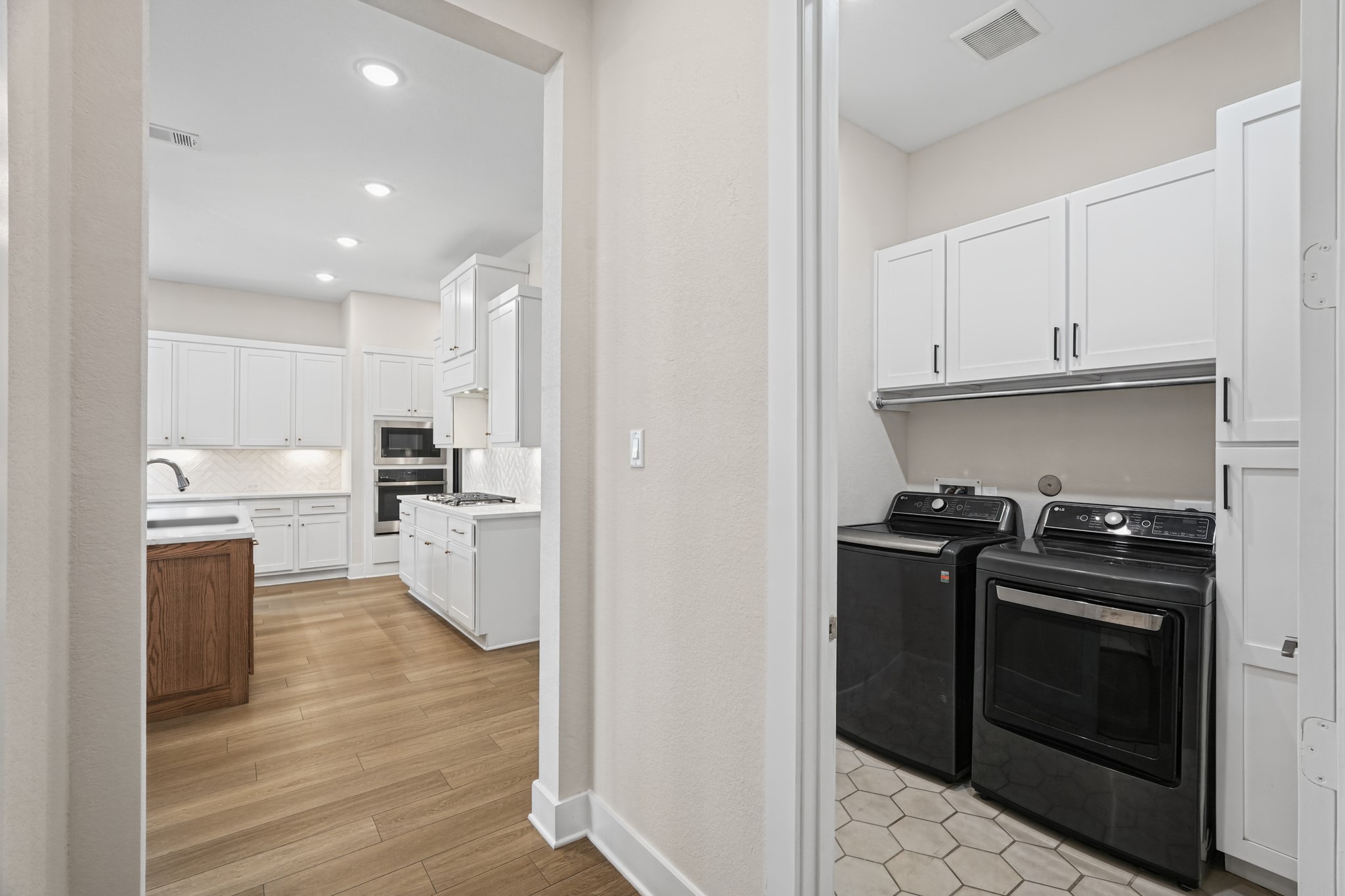 A gas range and additional cabinetry line the service side of the kitchen, with a pass-through to the main living area and quick access to the laundry room and garage entry.