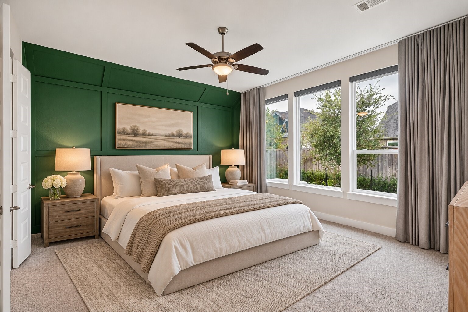 The private primary suite is tucked at the rear of the home, with a dramatic accent wall, a ceiling fan and large windows framing peaceful views of the backyard and pool area.