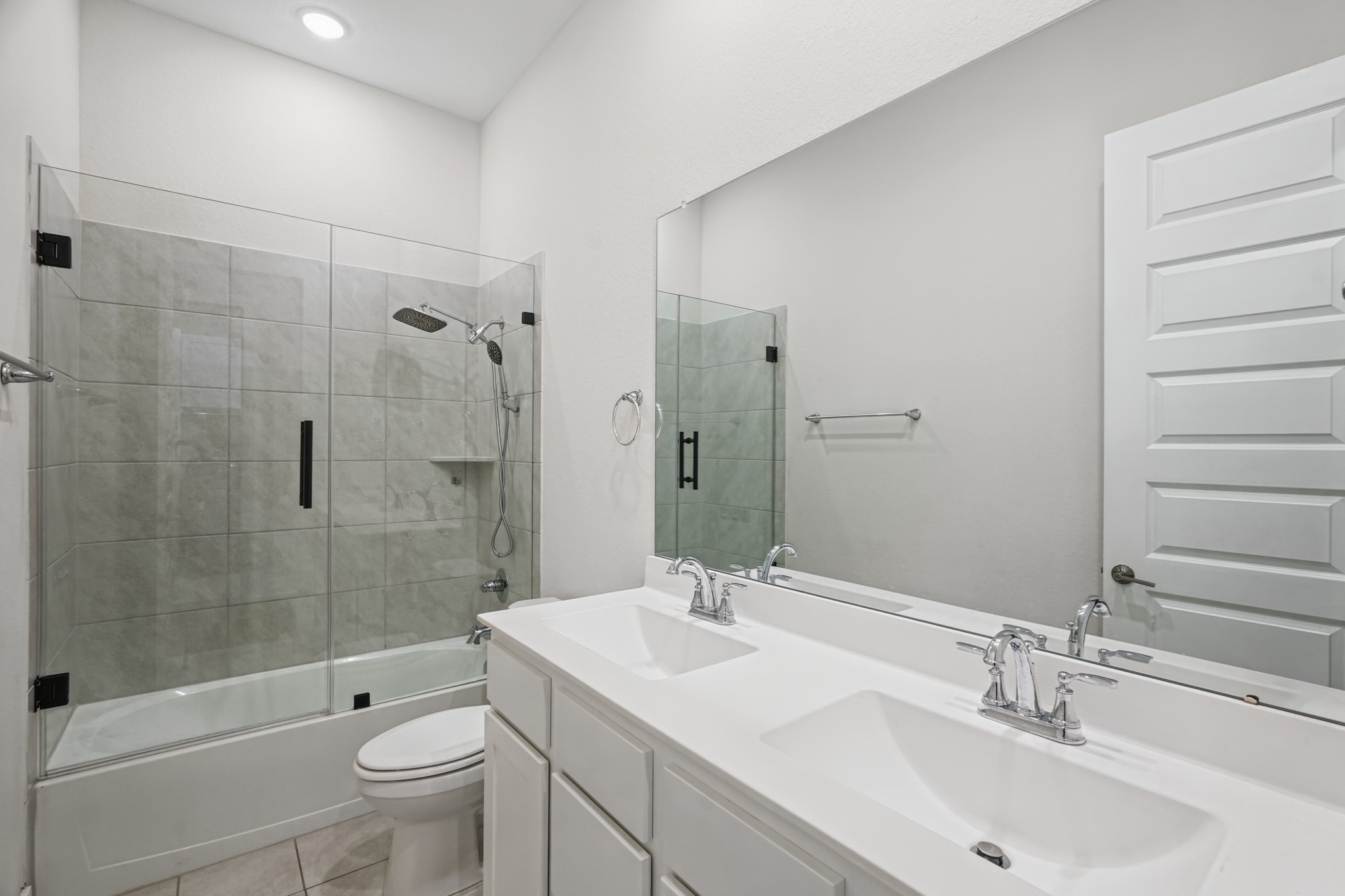 Secondary full bath offers a glass-enclosed shower, a wide vanity with storage below and bright lighting - nicely appointed for family members or for overnight guests.